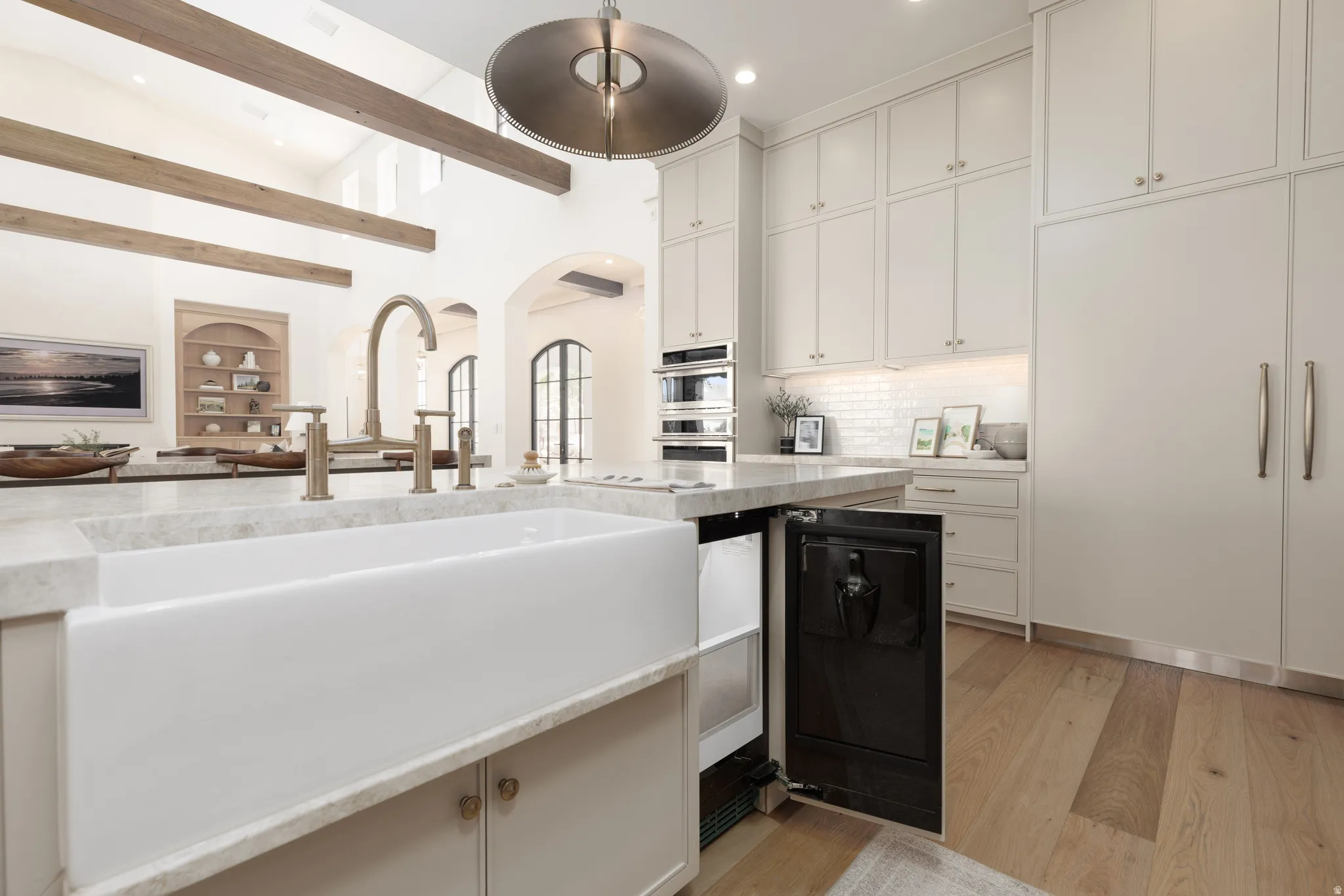 Kitchen featuring arched walkways, wine cooler, light wood finished floors, lofted ceiling, and decorative backsplash