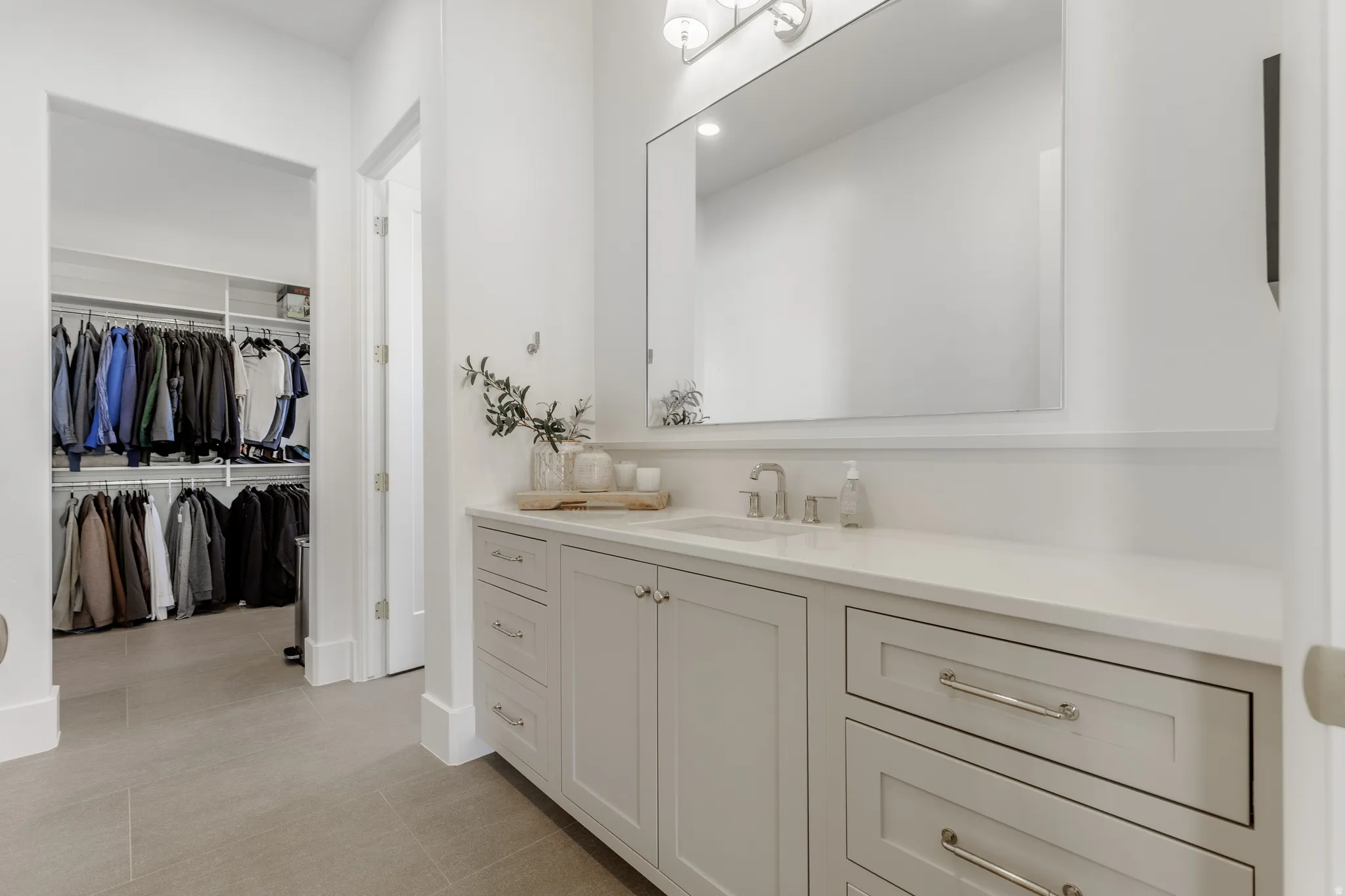 Full bathroom featuring vanity, a walk in closet, and light tile patterned floors