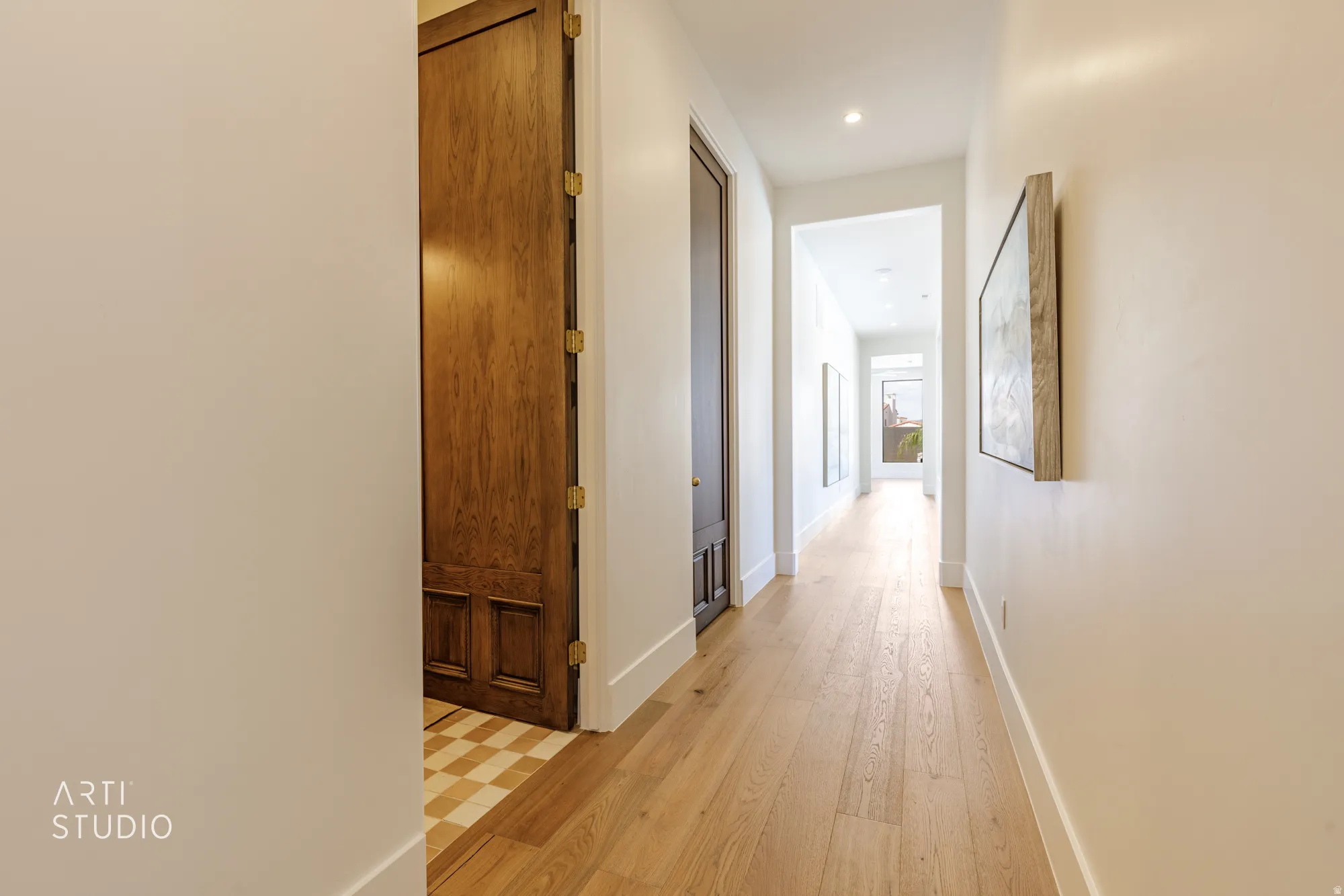 Hallway featuring light wood-finish flooring, recessed lighting, and bright white walls