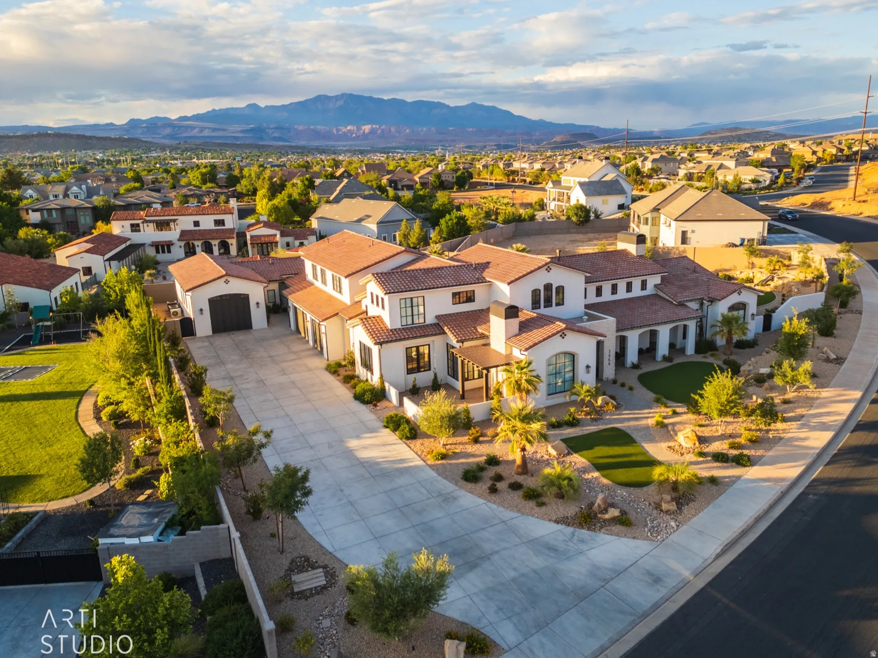 Spanish Colonial-style residence featuring a red tile roof, stucco exterior, and a spacious concrete driveway