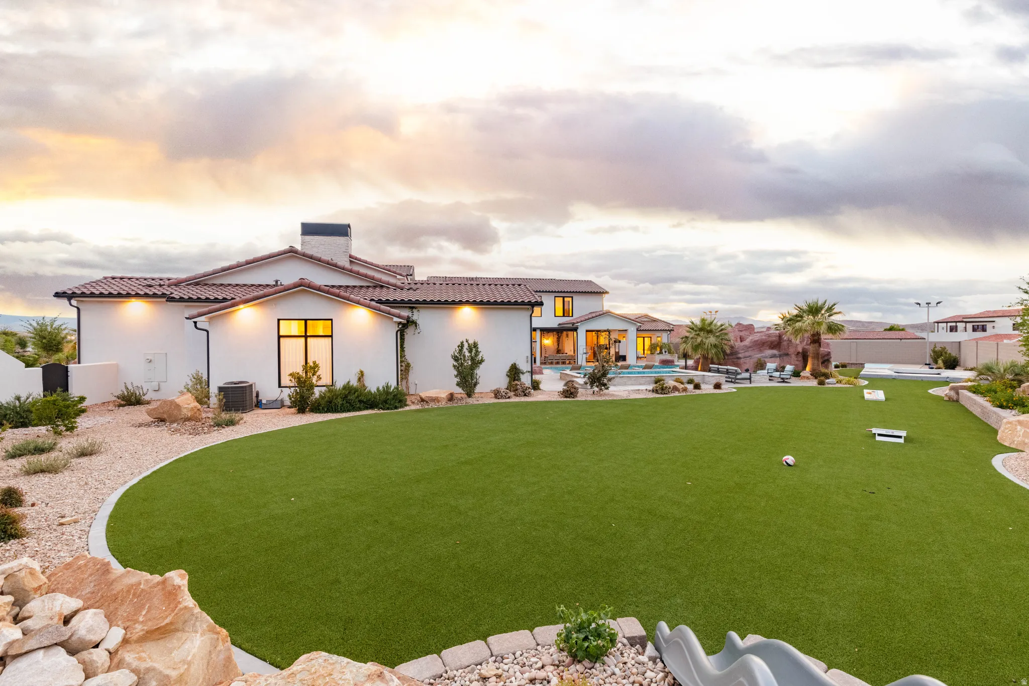 View of front of house featuring a fenced backyard, a patio area, an outdoor pool, a chimney, and stucco siding
