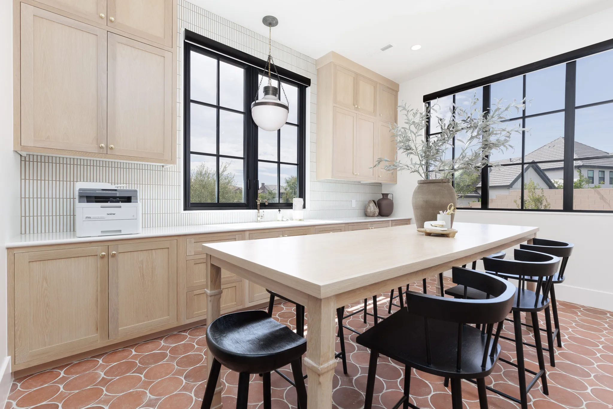 Kitchen featuring light wood finish cabinets, decorative backsplash, light countertops, and decorative light fixtures