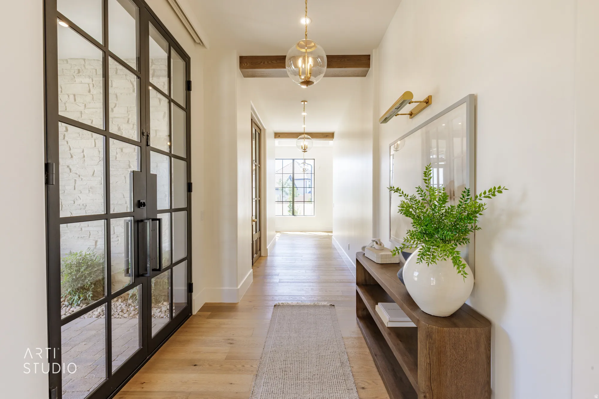 Entryway featuring a pair of black-framed glass doors, wood-finish flooring, exposed ceiling beams, and pendant lighting