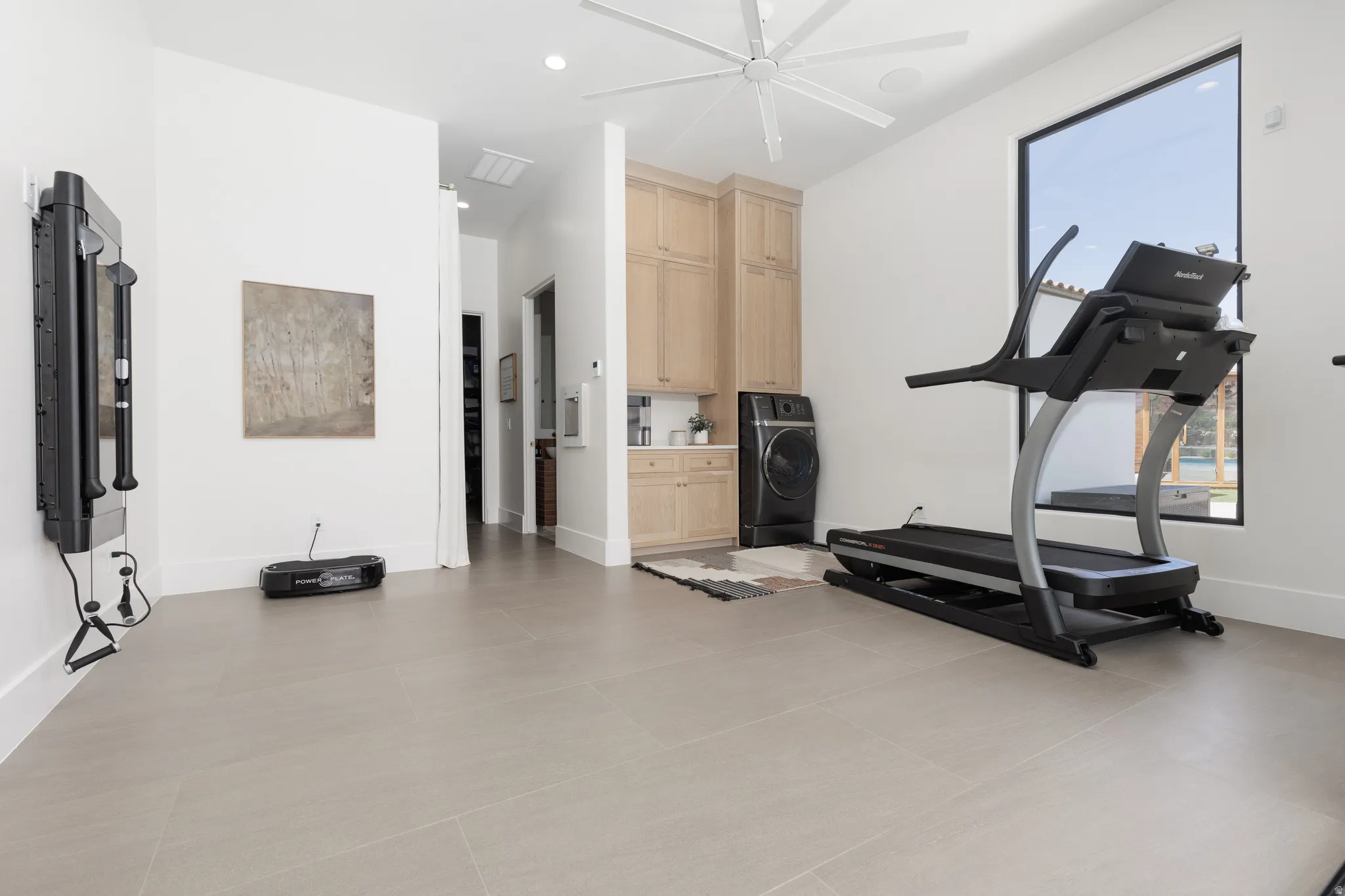Workout area with plenty of natural light, washer / clothes dryer, light tile patterned floors, and recessed lighting