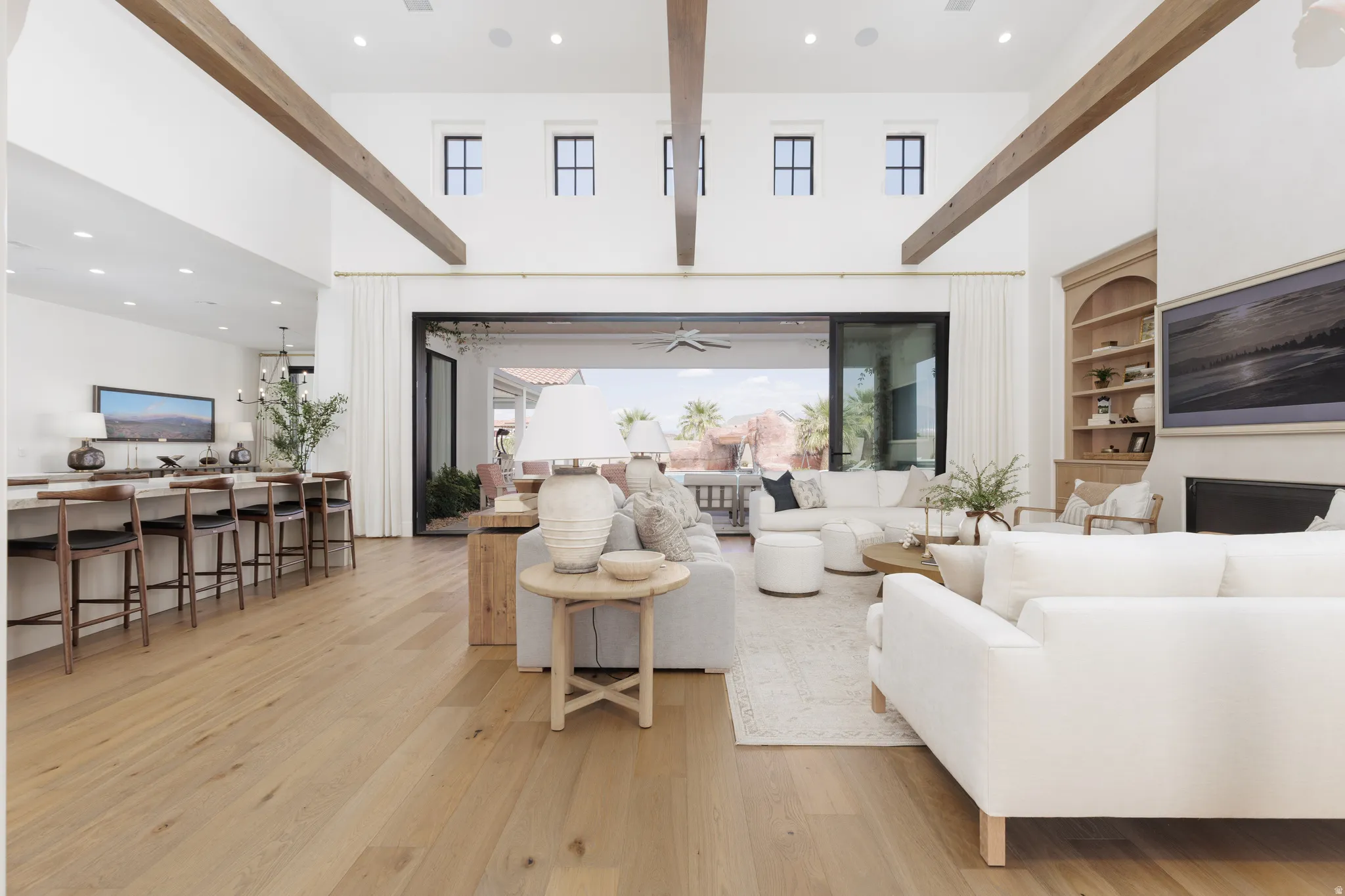 Living room featuring recessed lighting, light wood-style flooring, a high ceiling, built in shelves, and ceiling fan