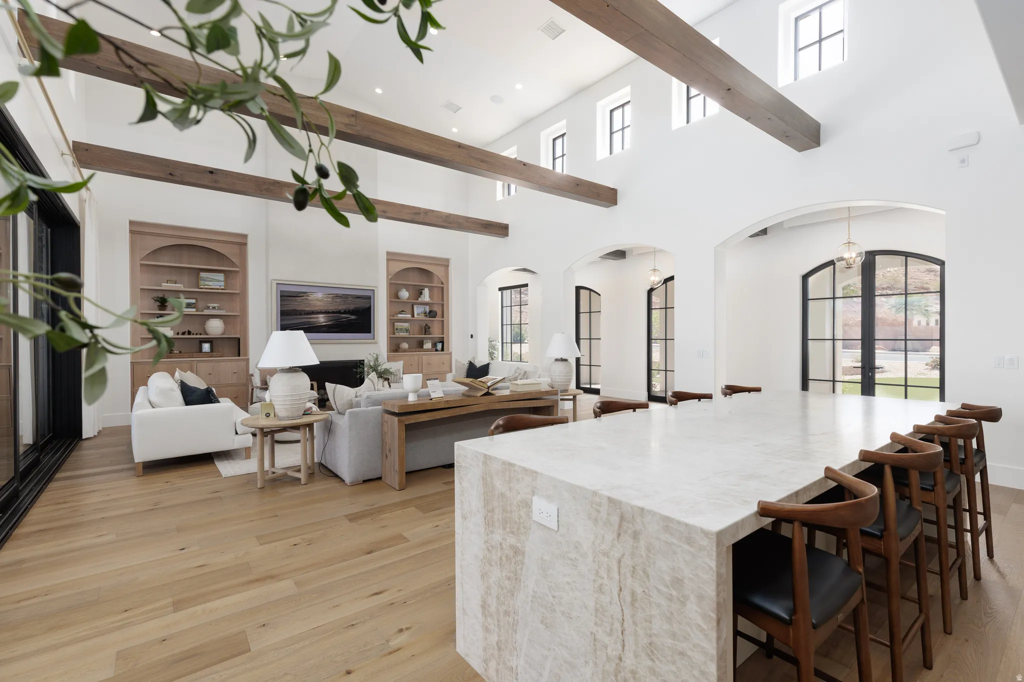 Kitchen with arched walkways, french doors, open floor plan, light wood finished floors, and a high ceiling