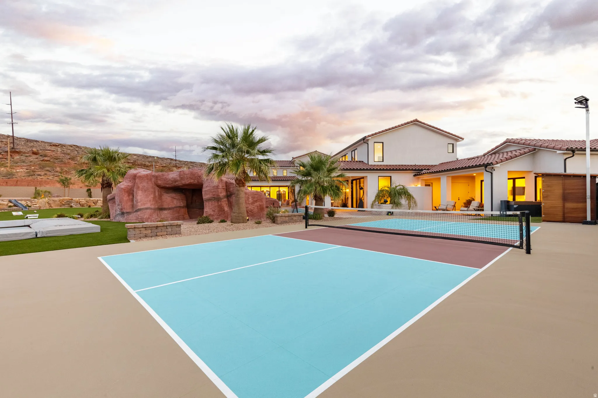 View of tennis court with a patio