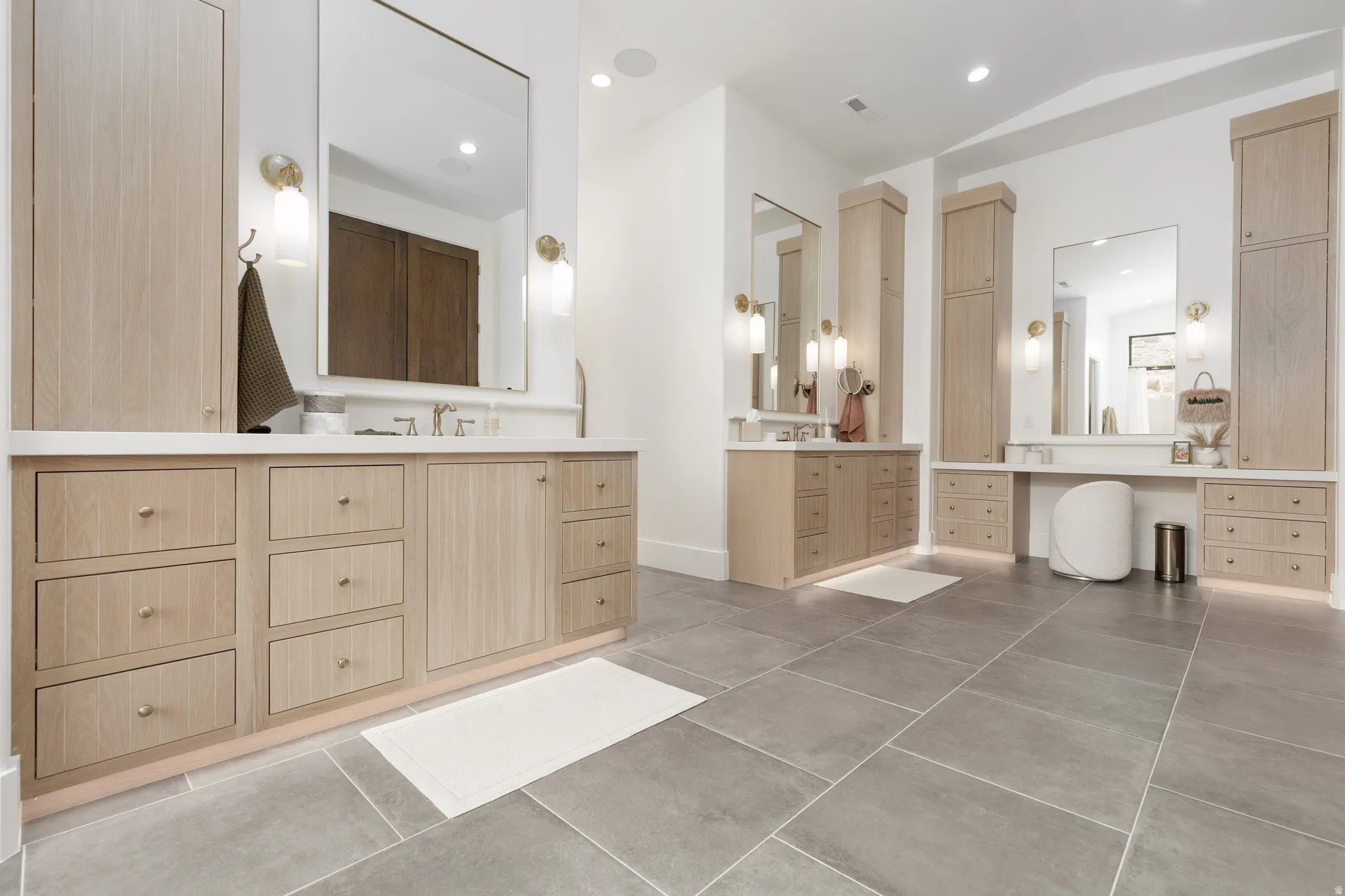 Bathroom with two vanities, recessed lighting, vaulted ceiling, and light tile patterned floors