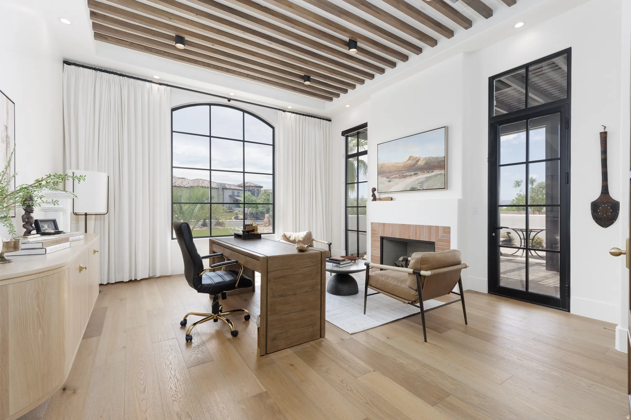 Office area featuring a brick fireplace and light wood-style floors