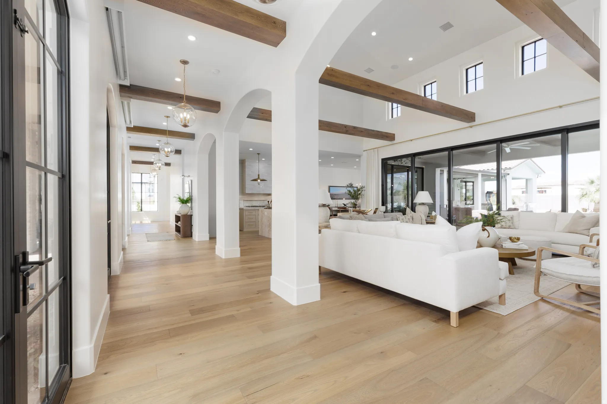 Living room featuring light wood-type flooring, recessed lighting, beam ceiling, and arched walkways