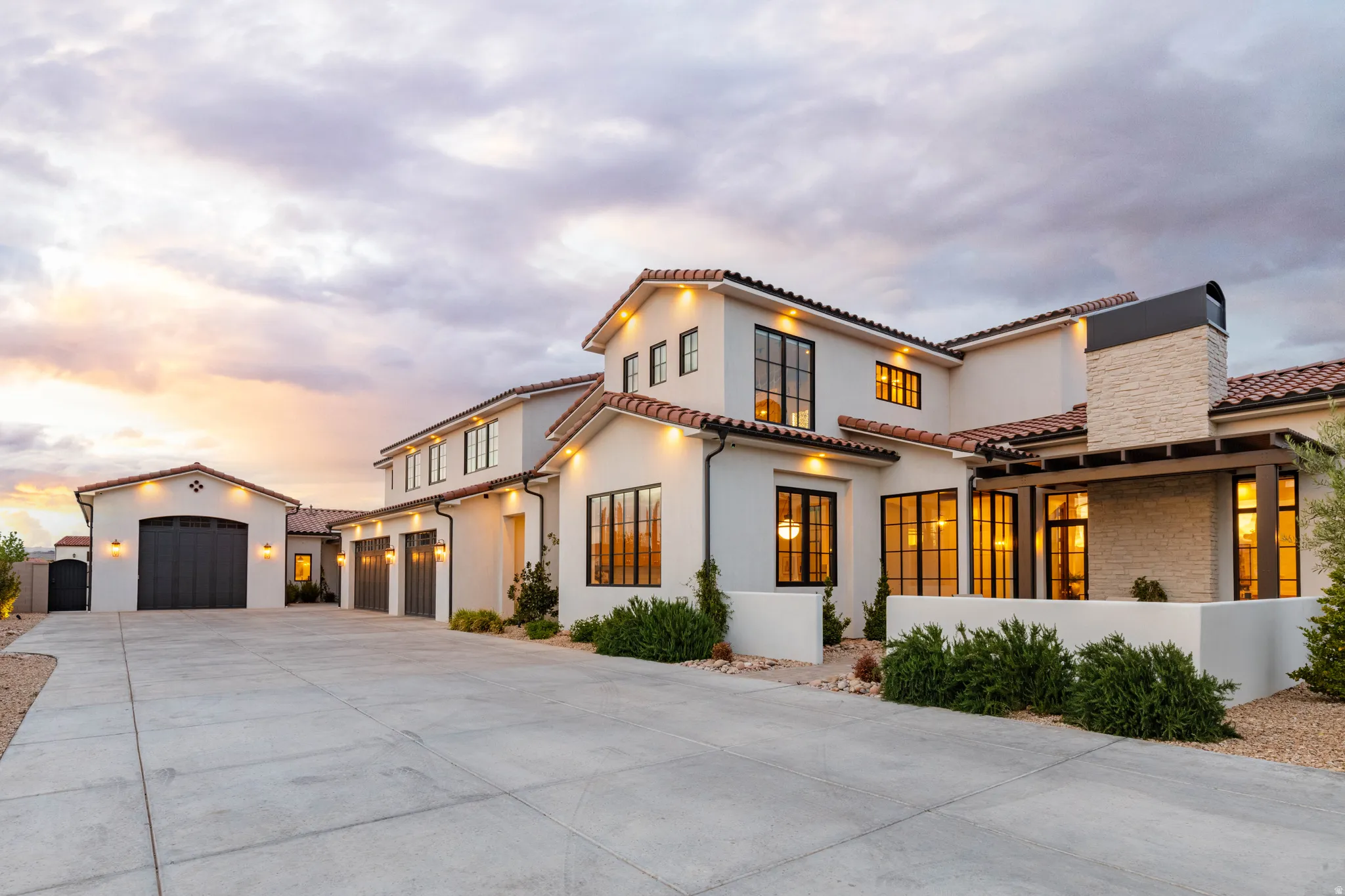 Mediterranean / spanish-style home featuring a chimney, concrete driveway, stucco siding, and a tiled roof