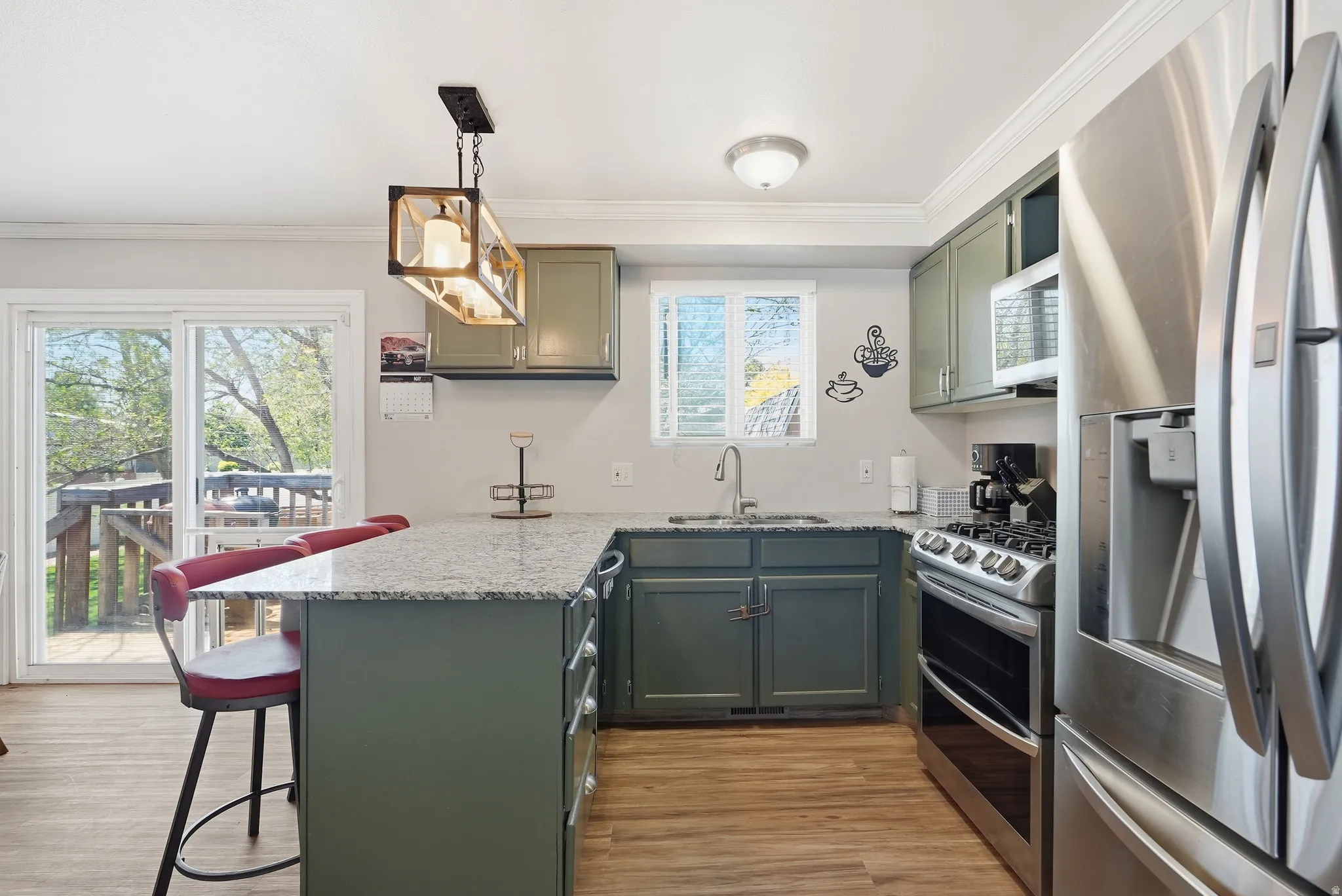 Kitchen featuring wood-finish flooring, granite-style countertops, and sage cabinetry