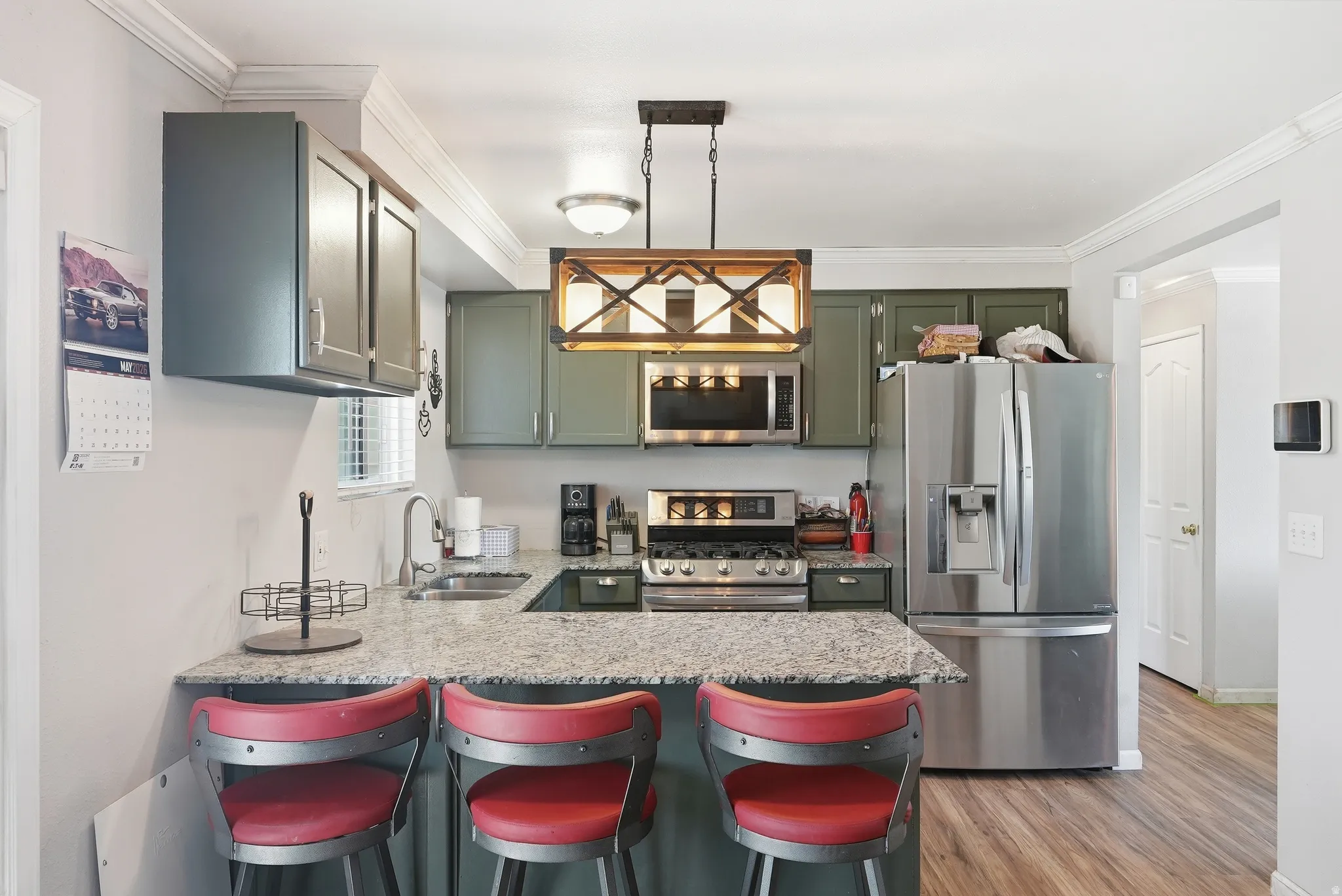 Kitchen featuring granite countertops, stainless steel appliances, wood-finish flooring, recessed lighting, and crown molding details
