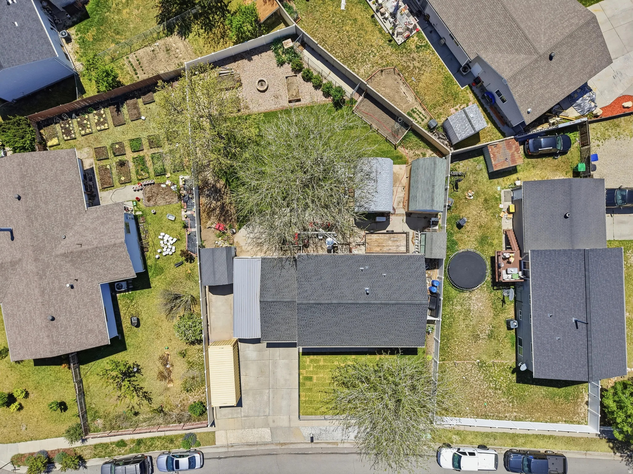 Aerial perspective showcasing the property with a dark shingle roof, concrete driveway, and front lawn