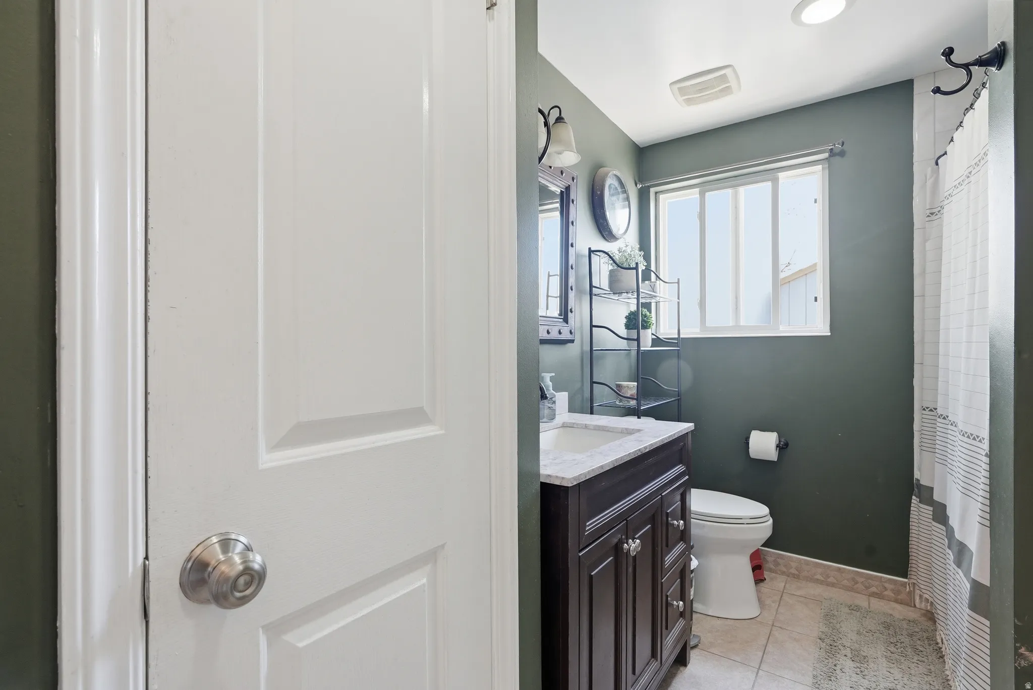 Bathroom featuring a single vanity with wood-finish cabinetry, a white countertop, and a white basin