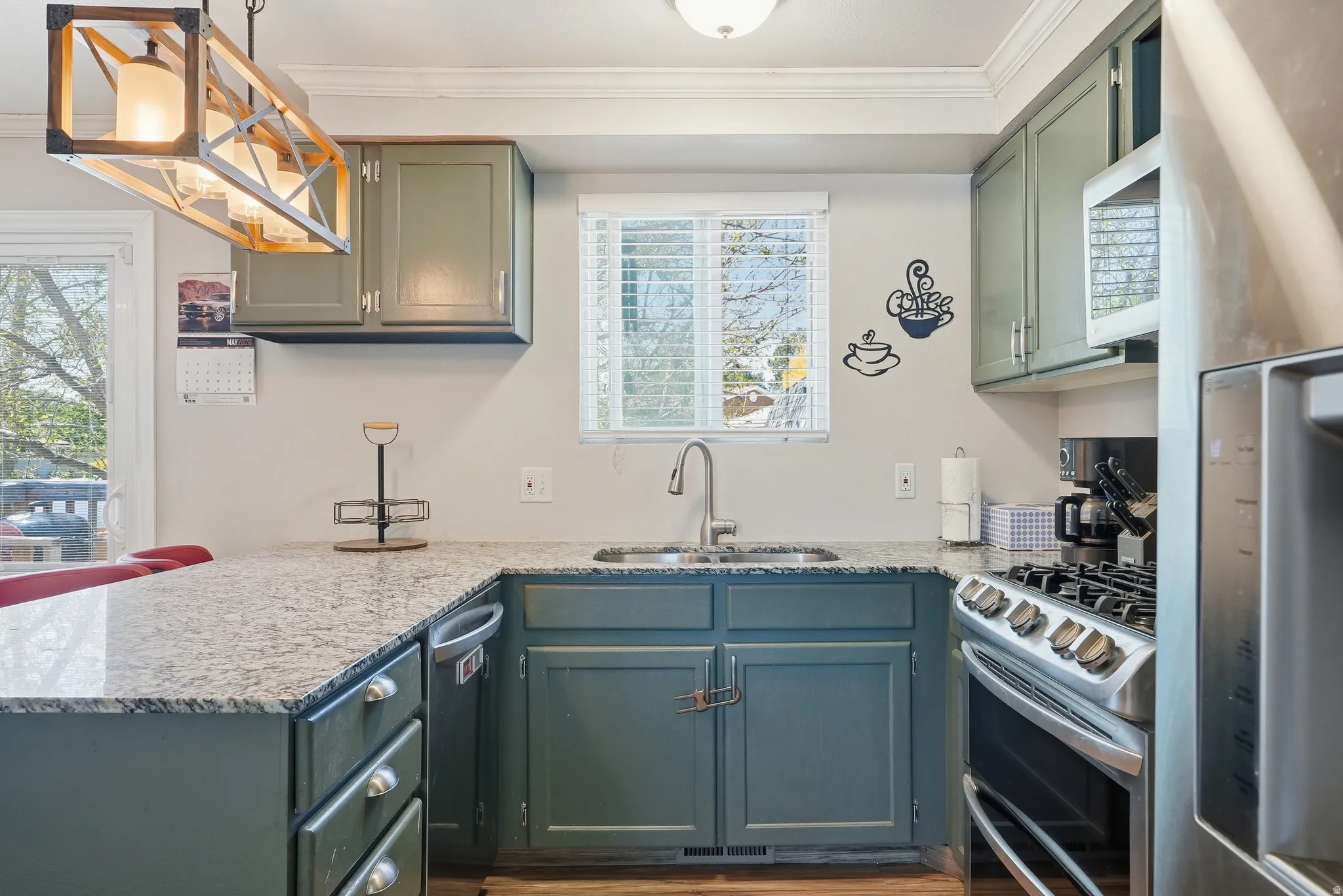 U-shaped kitchen featuring granite countertops, painted cabinetry, and stainless steel appliances