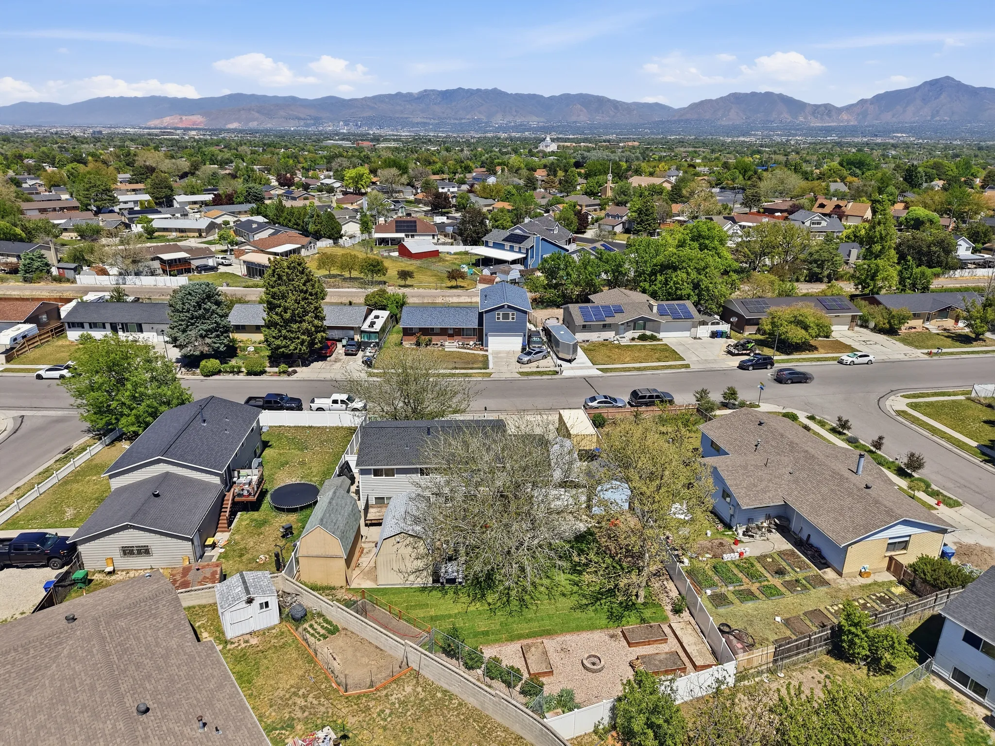 Expansive property featuring a spacious backyard, raised garden beds, a dedicated fire pit area, and mature trees