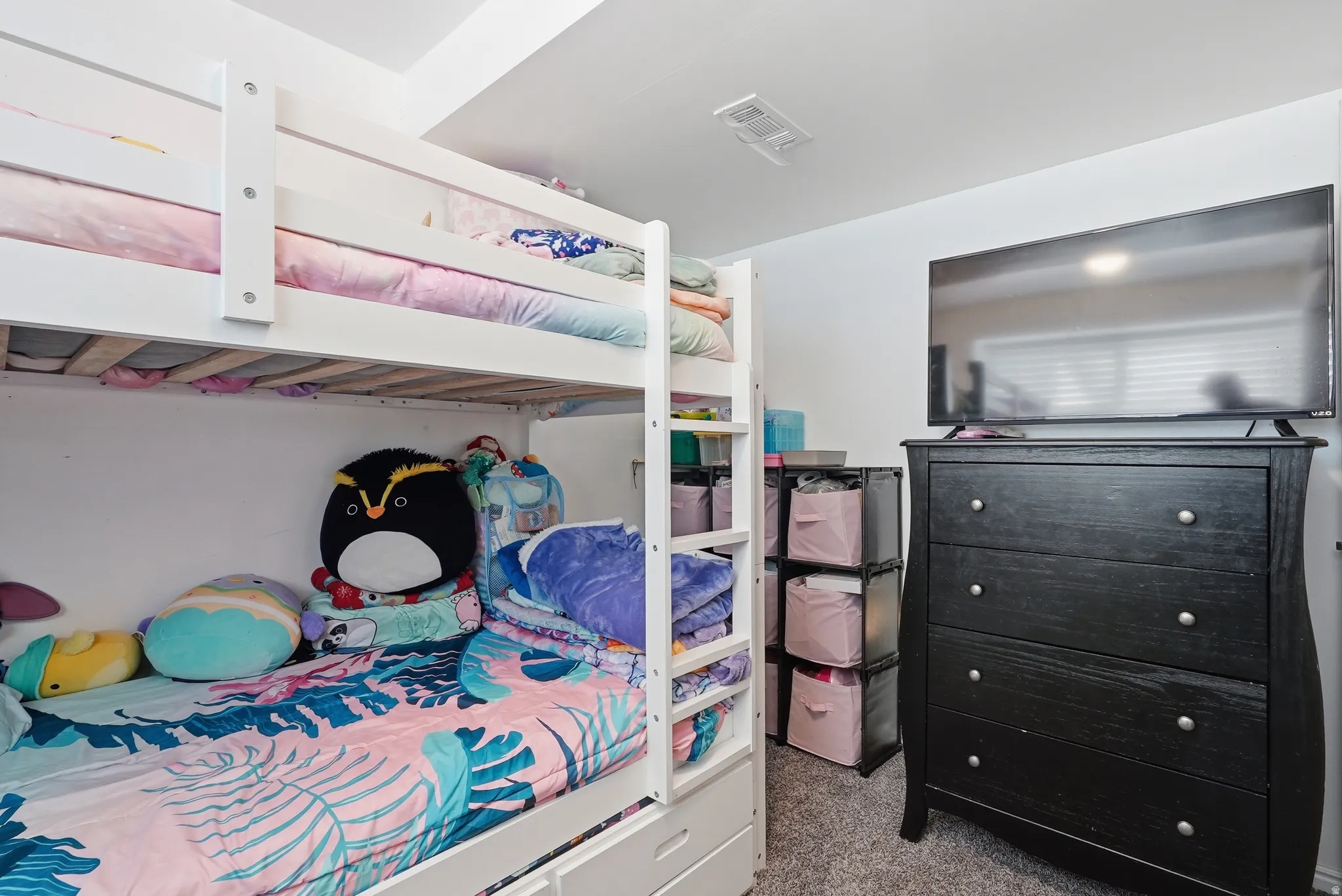 Recessed lighting illuminates this room, featuring a white bunk bed with integrated storage drawers