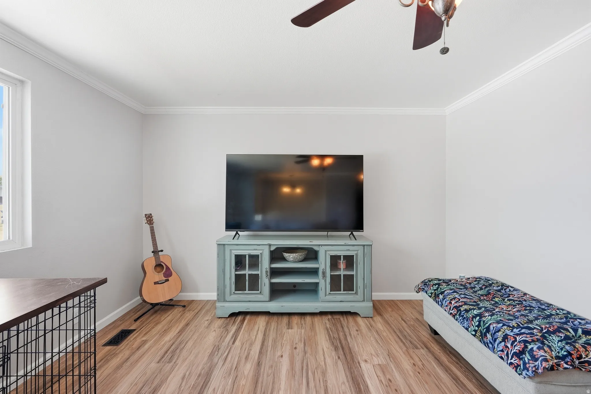 Living space featuring wood-finish flooring, light gray wall paint, and white crown molding