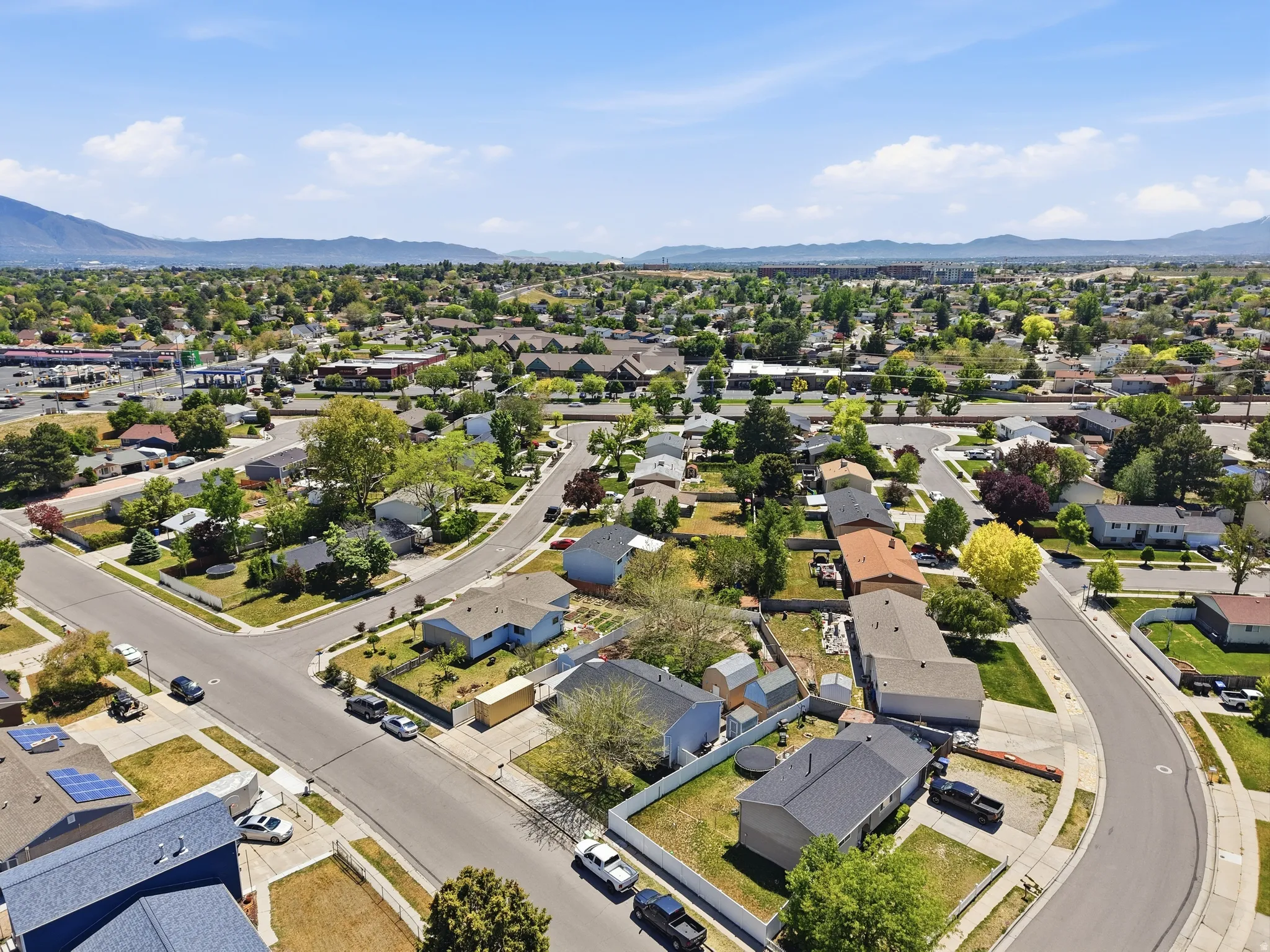 Residential neighborhood featuring mature trees, paved streets, and a mountainous backdrop