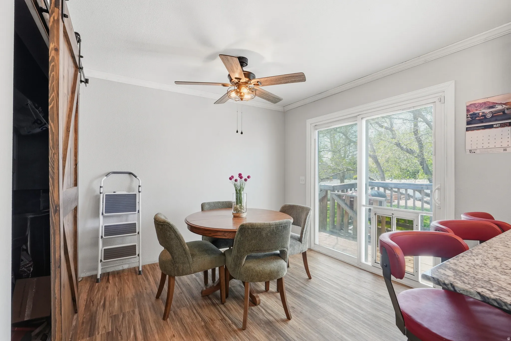 Dining area with wood-finish flooring, sliding glass door, and ceiling fan with integrated lighting