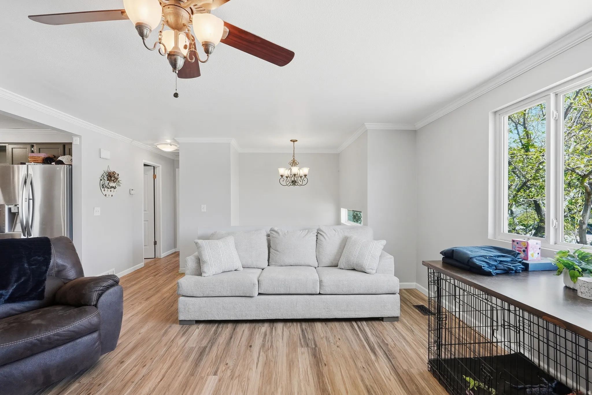 Open living area with wood-finish flooring, crown molding, and recessed lighting