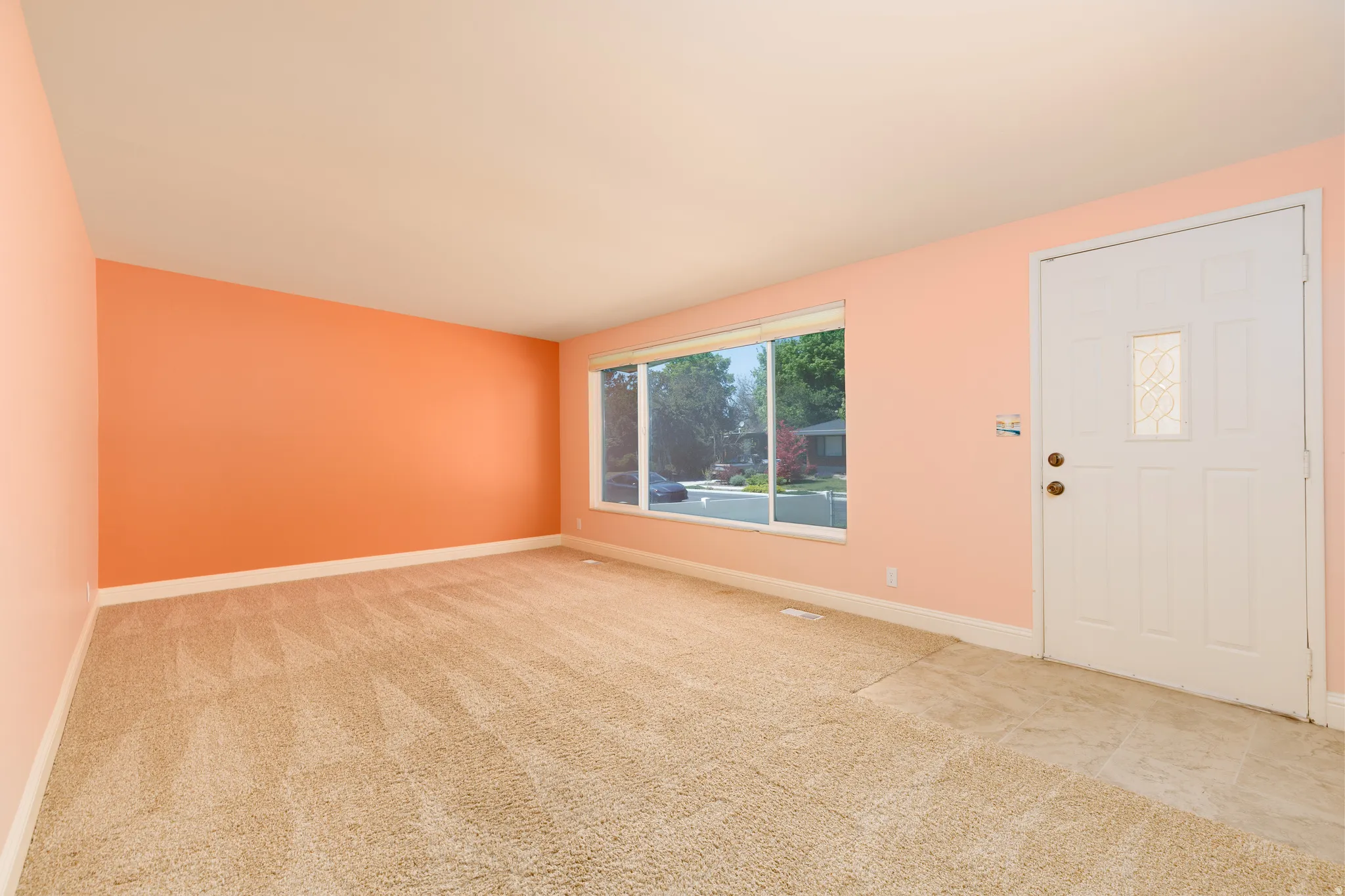 Spacious room featuring broad picture windows, light-colored walls, white trim, and neutral carpeting