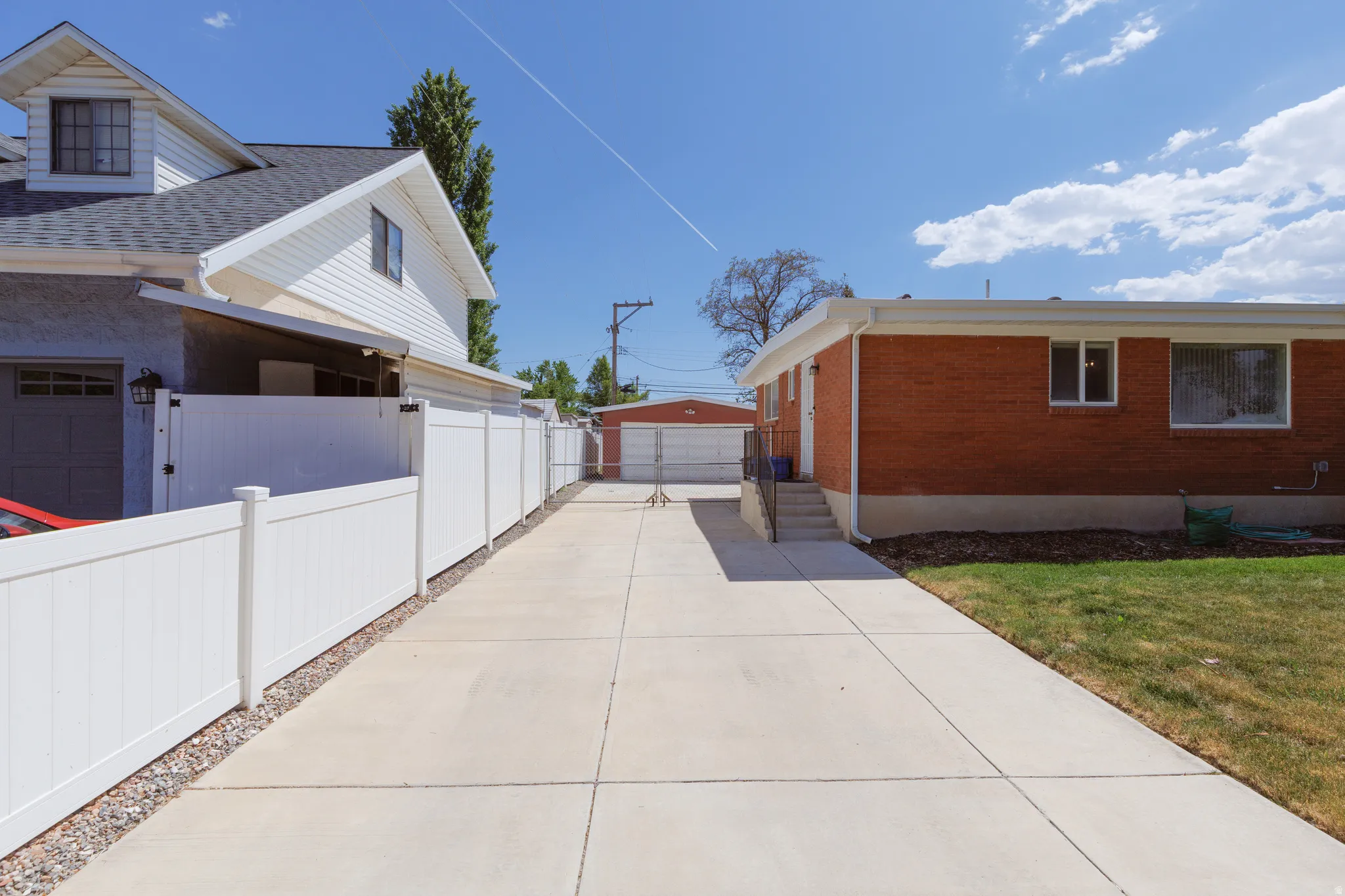 Expansive concrete driveway framed by a white privacy fence