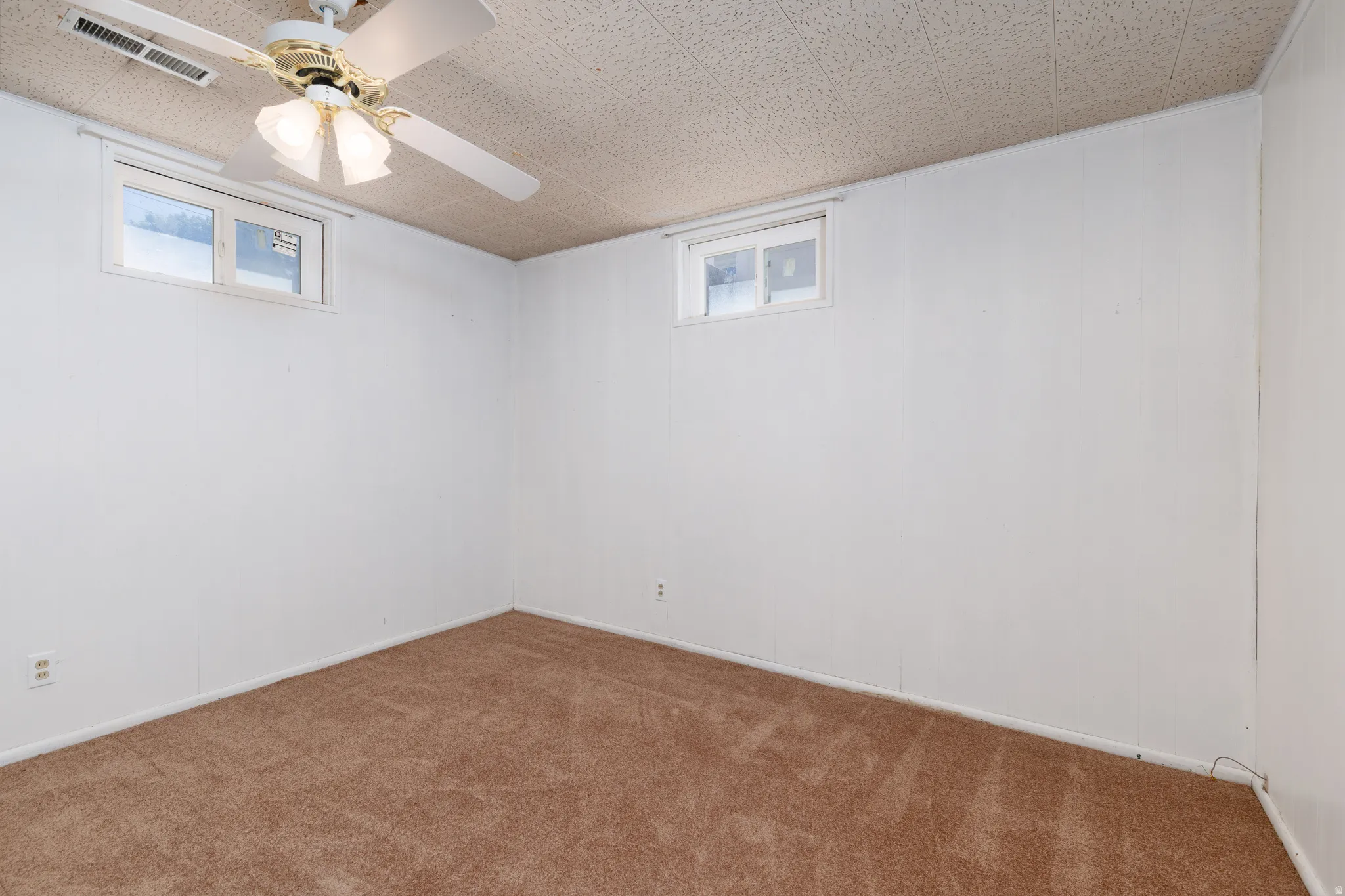 Bedroom #5 featuring a ceiling fan with integrated lighting, two windows, and white painted walls