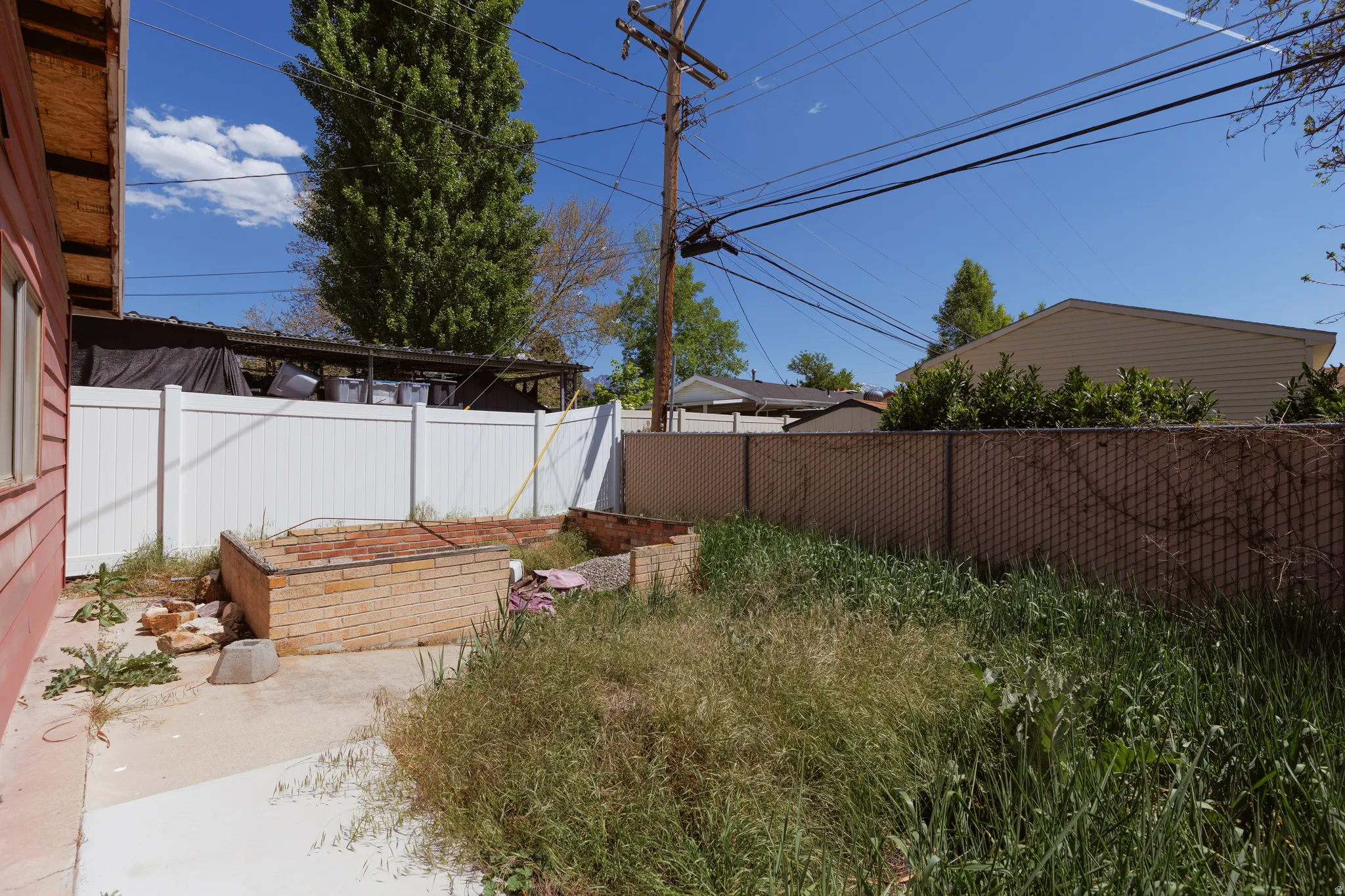 Rear yard with a concrete patio area and an adjacent planting bed constructed from brick