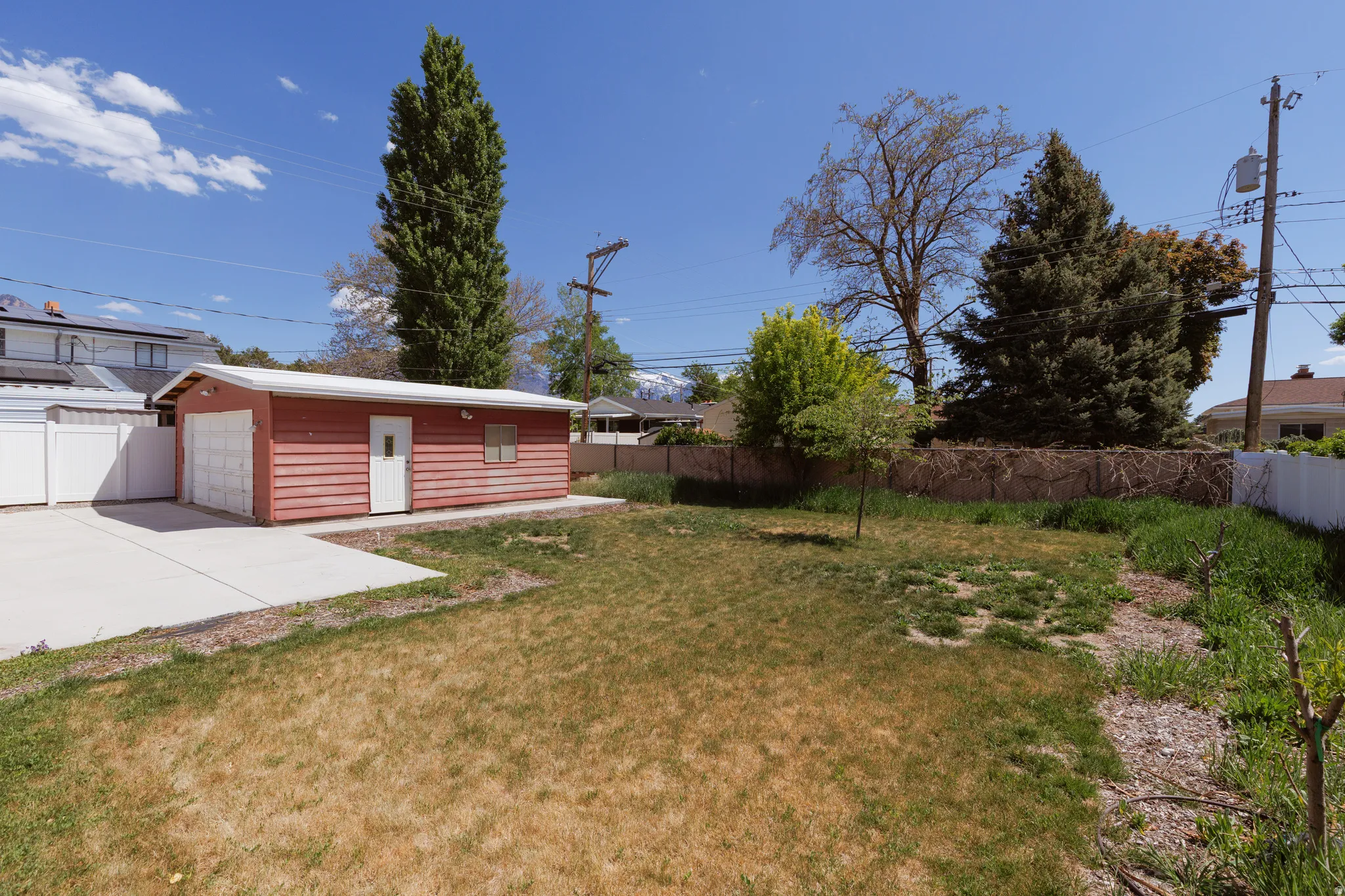 Detached garage with red siding, white overhead door, and white entry door