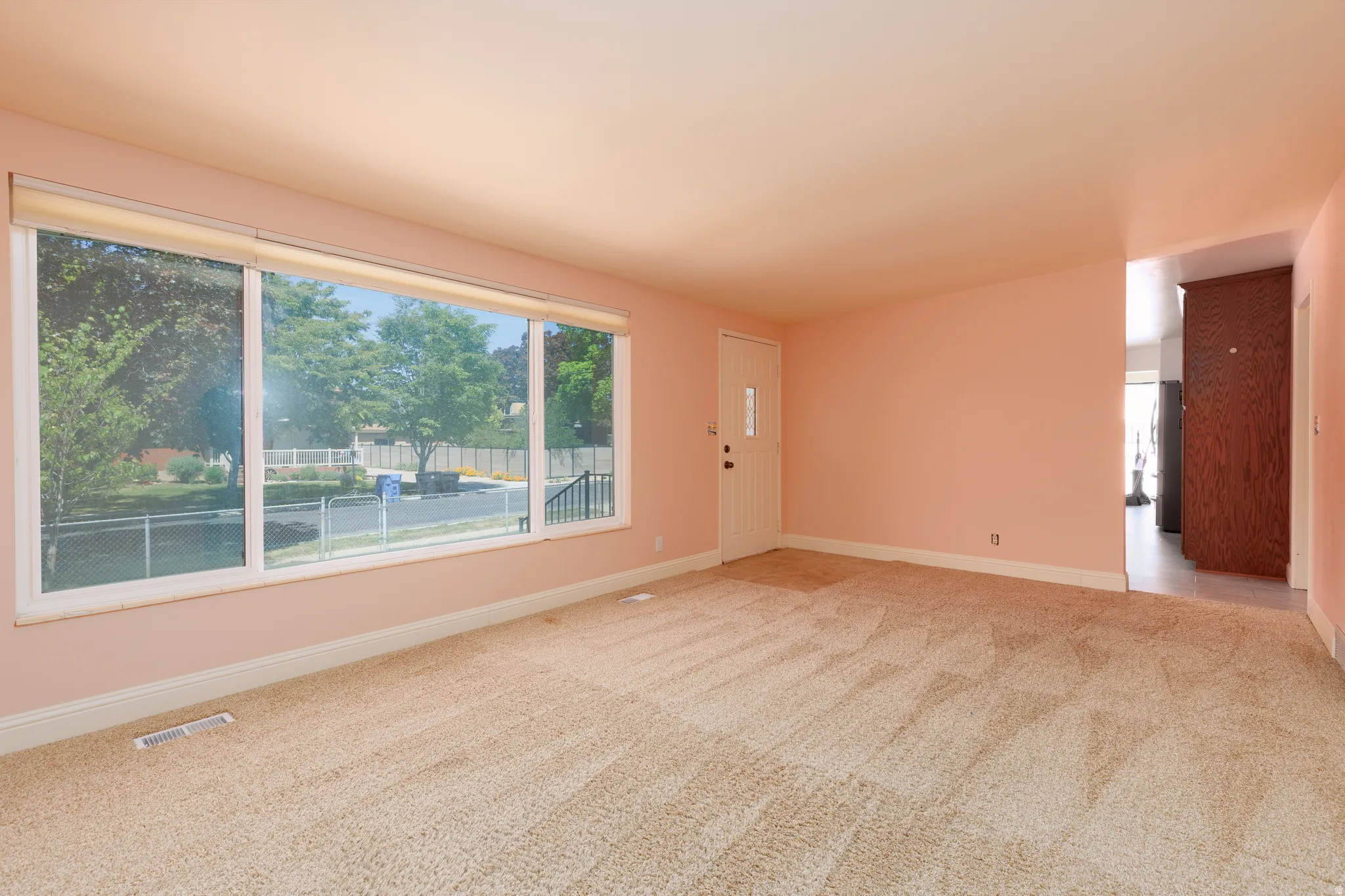 Spacious interior room with light-colored carpet flooring and a wide picture window