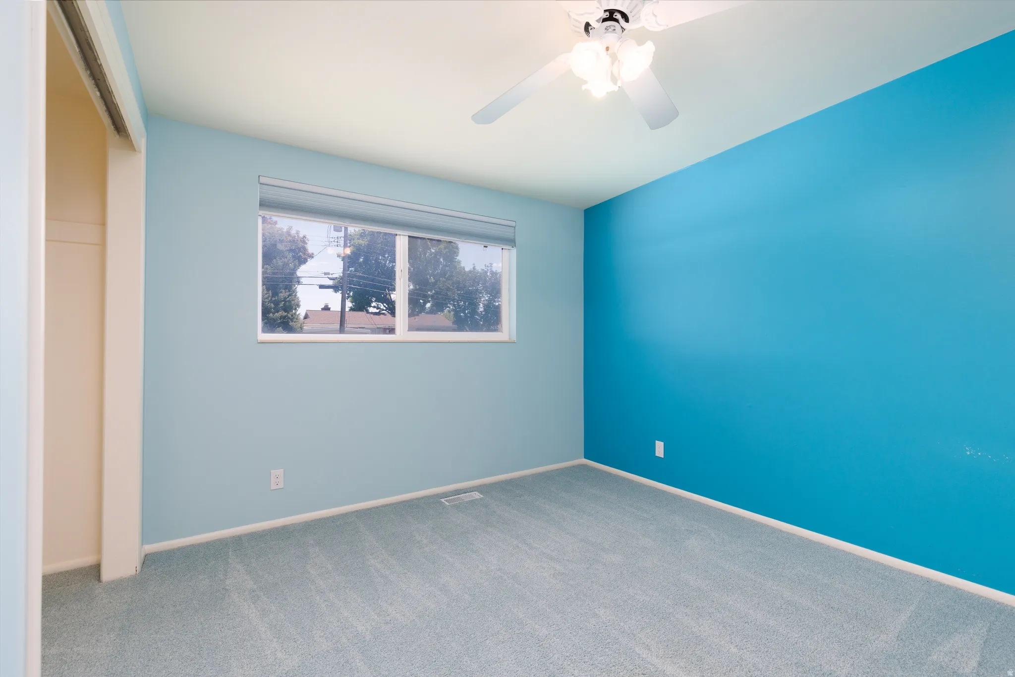 Bedroom #3 featuring a window, light blue carpeting, and a ceiling fan with integrated lighting