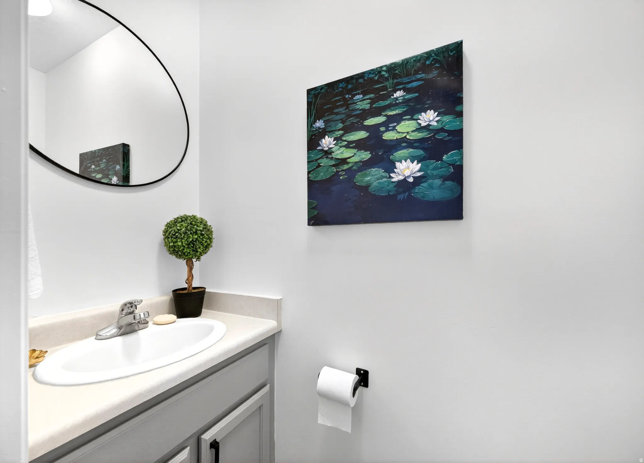 Half bath on main floor.Vanity featuring a white oval sink, chrome faucet, and light-colored countertop