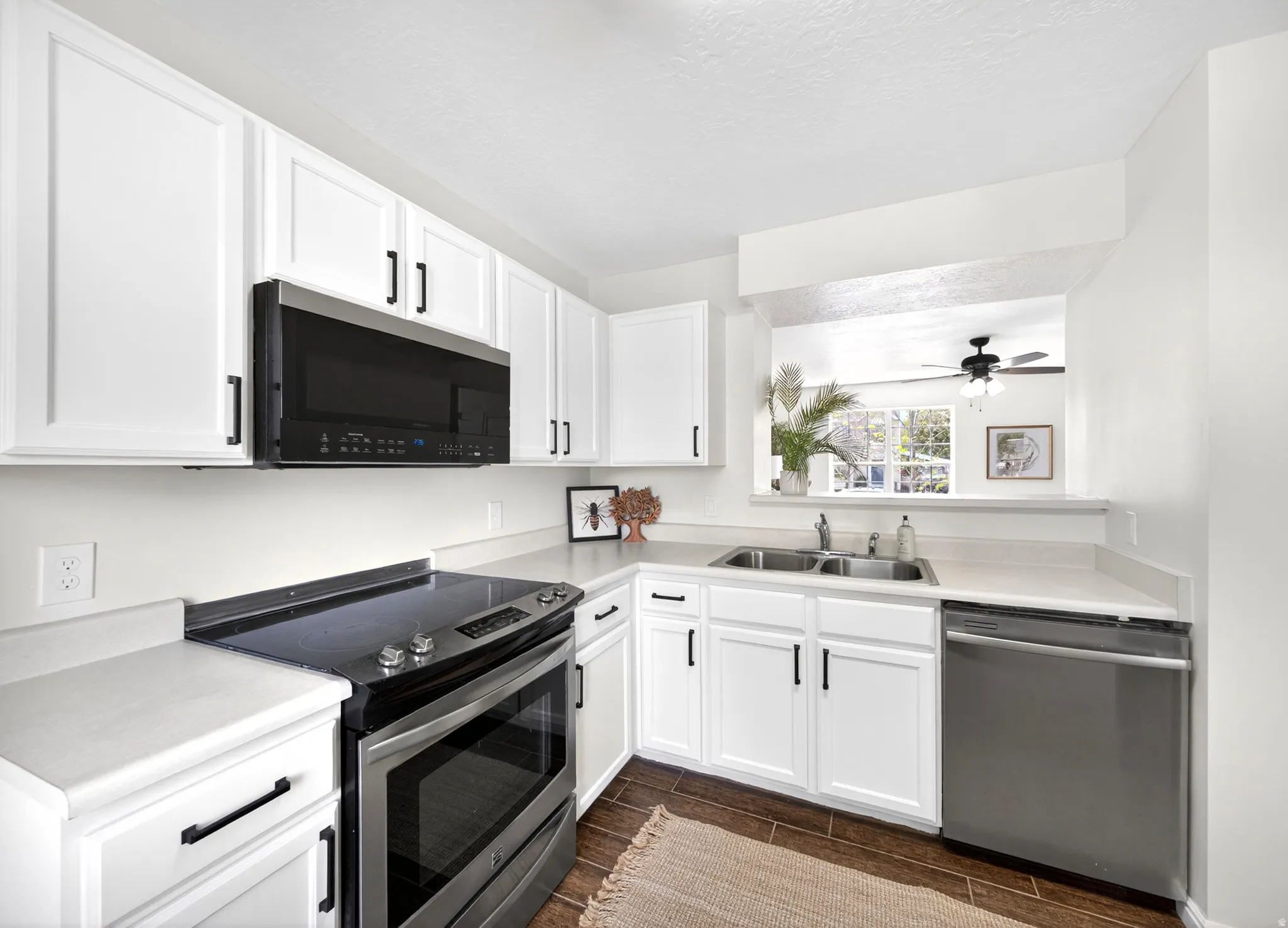 Kitchen featuring white shaker cabinetry with black hardware, stainless steel appliances, and a double basin sink