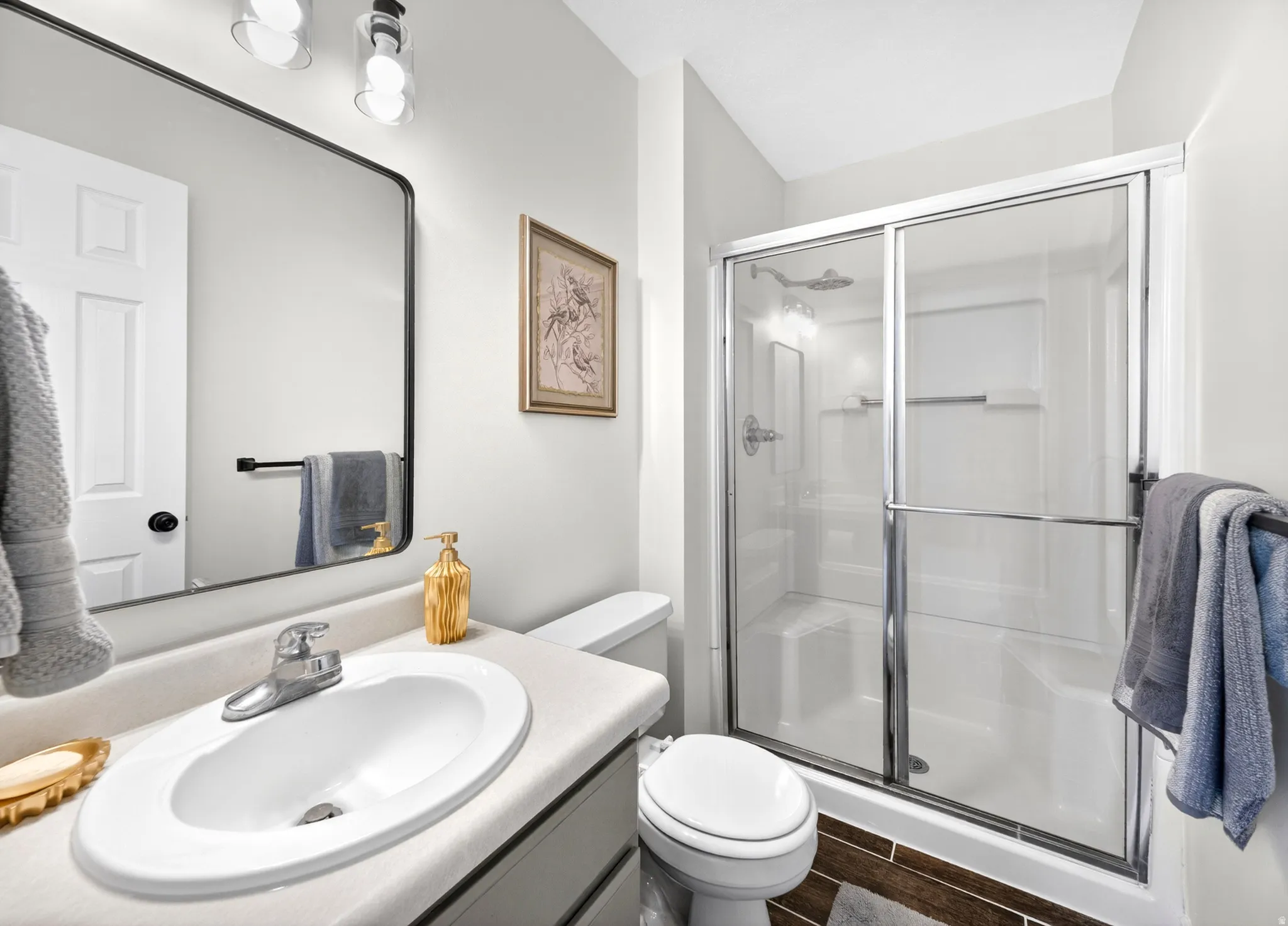 Master Bathroom featuring a glass-enclosed shower with sliding doors, a single vanity with an oval sink, and a framed mirror