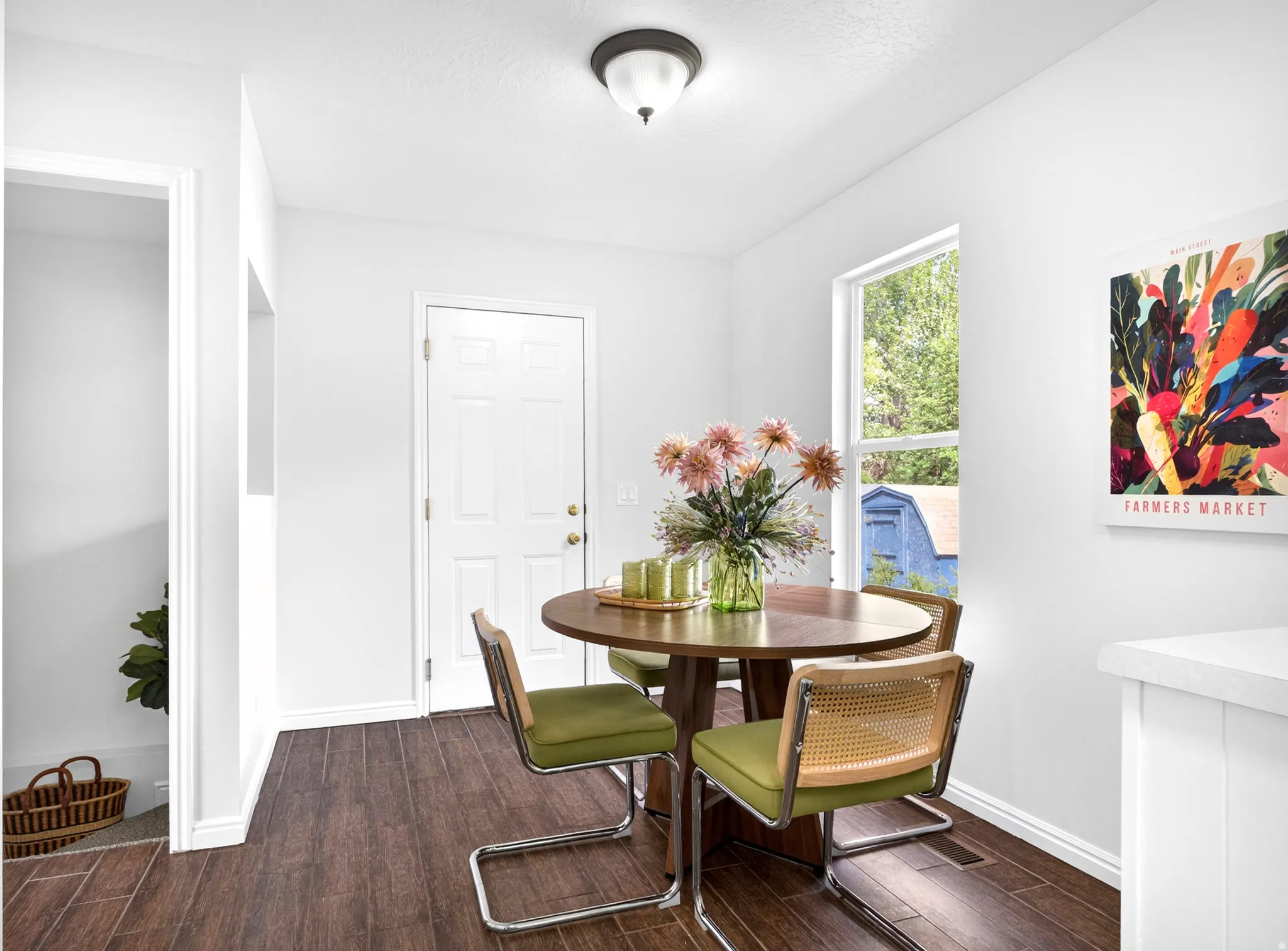 Dining area featuring dark wood-finish flooring, white walls, and a large window