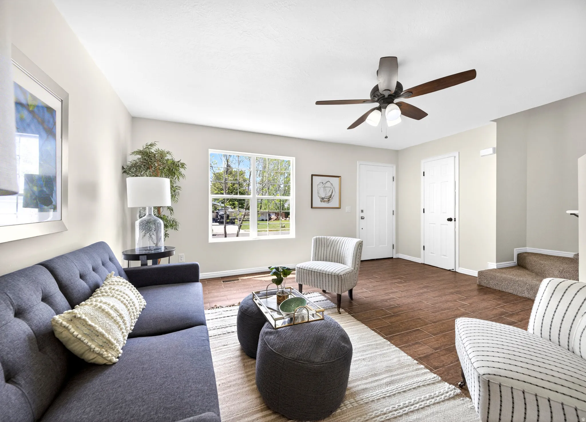 Bright living area featuring wood-finish flooring and a ceiling fan with integrated lighting