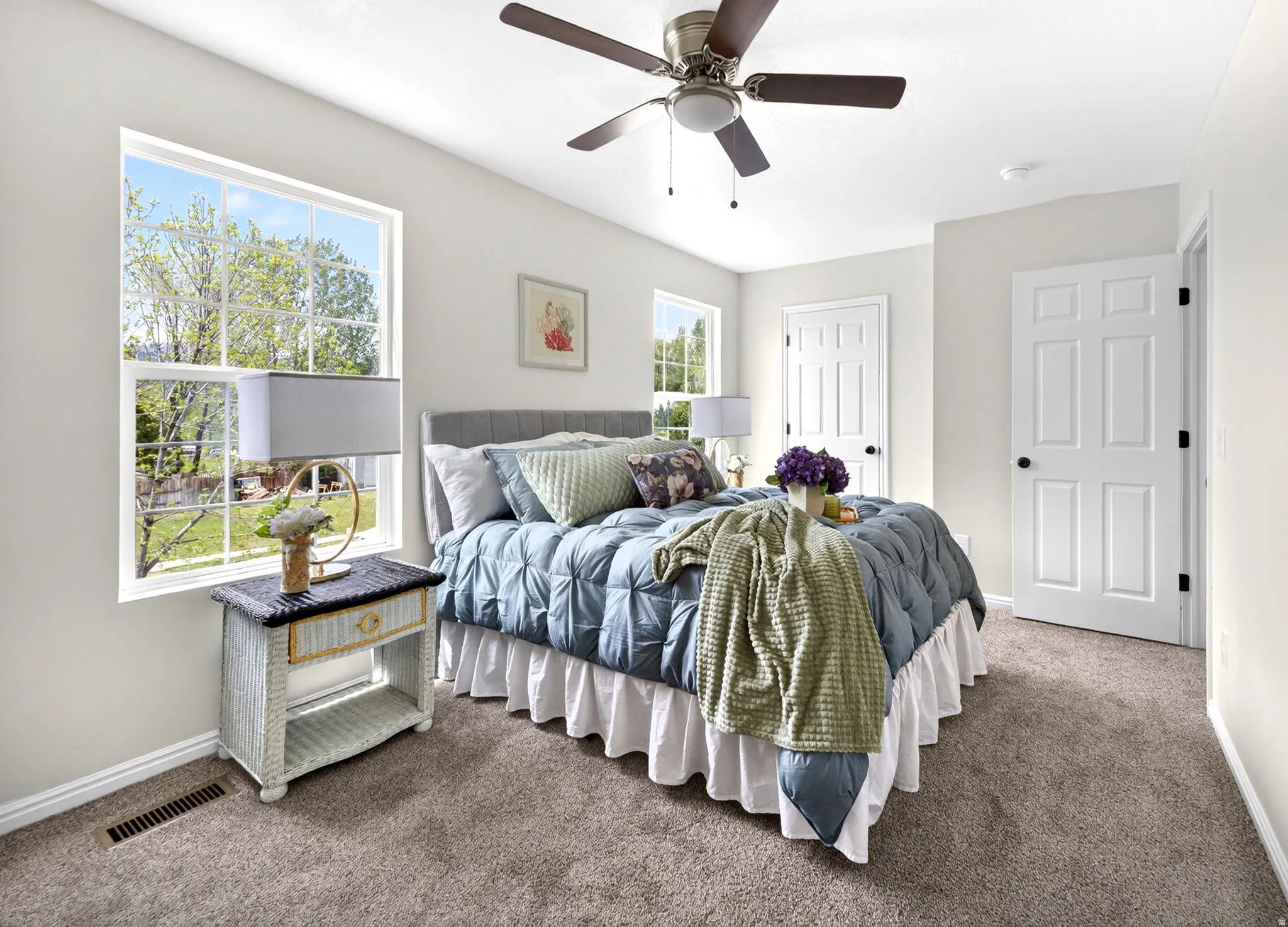 Carpeted bedroom featuring a ceiling fan with integrated lighting, white baseboards, and double-pane windows