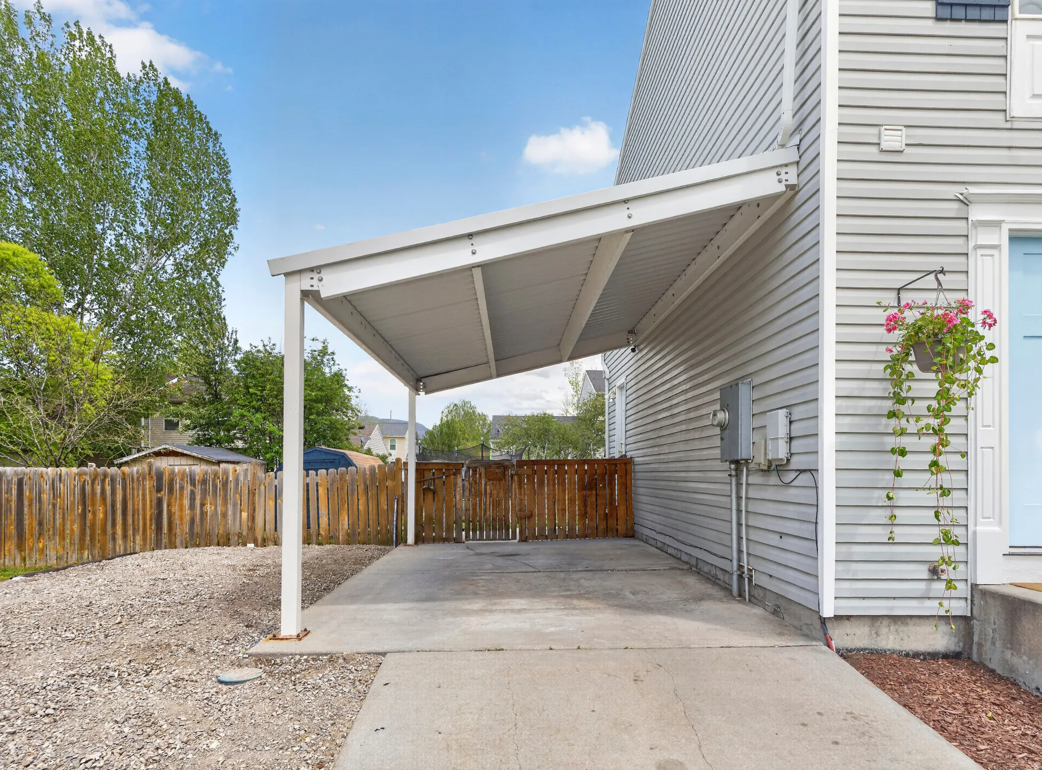 Covered carport providing sheltered parking and secondary parking with gravel
