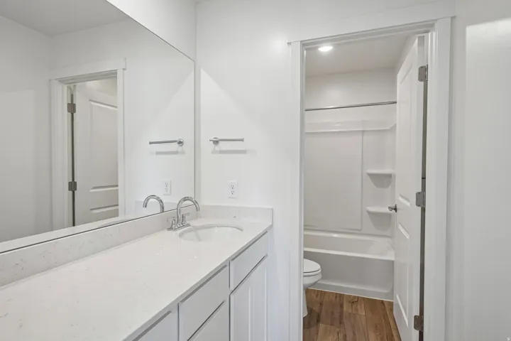 Vanity with a single basin sink, chrome faucet, and expansive wall-mounted mirror