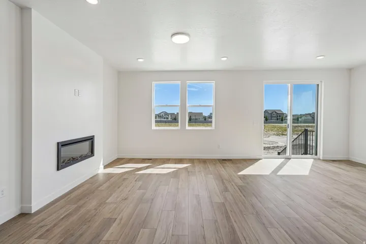 Wood-finish flooring, recessed lighting, and a wall-mounted fireplace