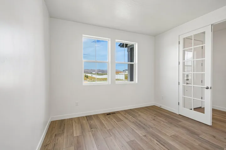 Wood-finish flooring, white walls, and a white framed window