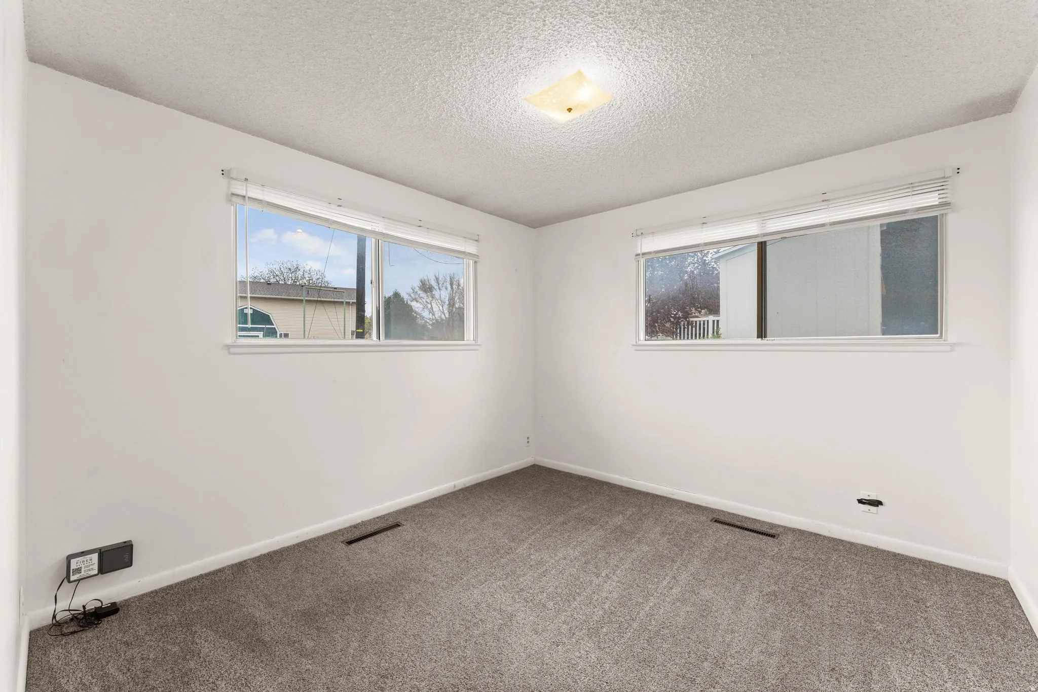 Carpeted empty room featuring a textured ceiling and baseboards