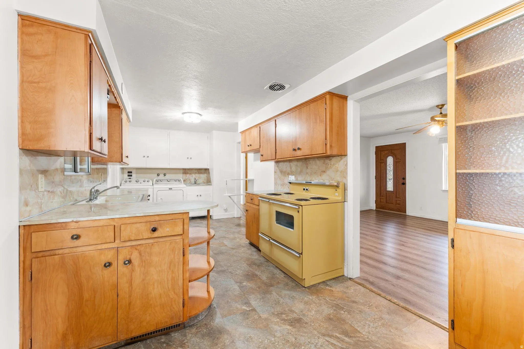Kitchen with a peninsula, range with electric cooktop, light countertops, washer and clothes dryer, and a textured ceiling