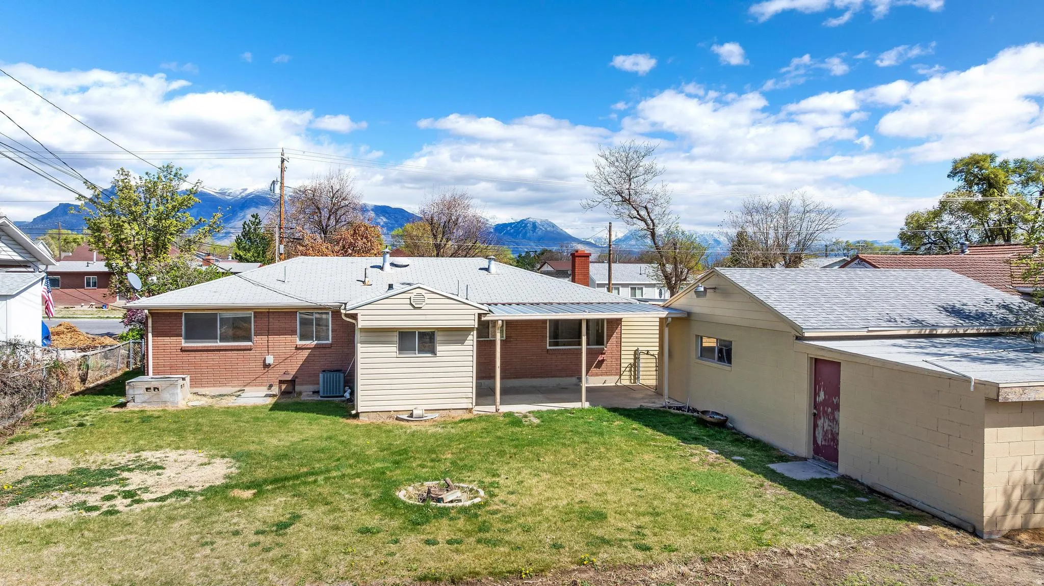 Back of house with a patio, a chimney, a mountain view, and brick siding