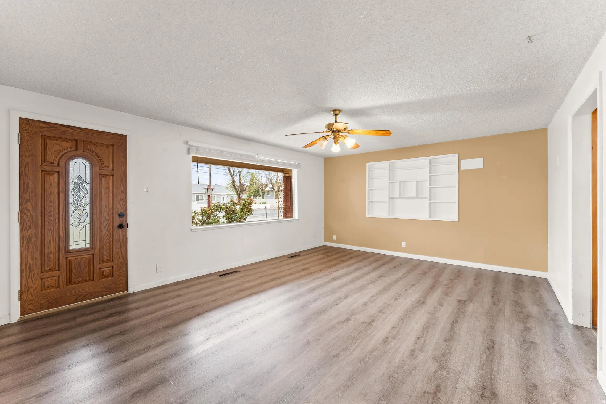 Foyer entrance featuring a textured ceiling, light wood-style flooring, and ceiling fan