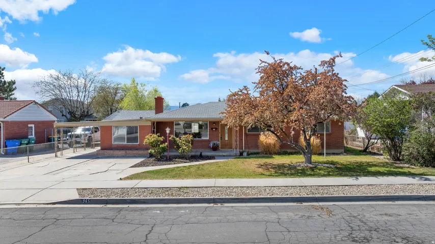 Ranch-style home with a porch, brick siding, a front lawn, and a chimney