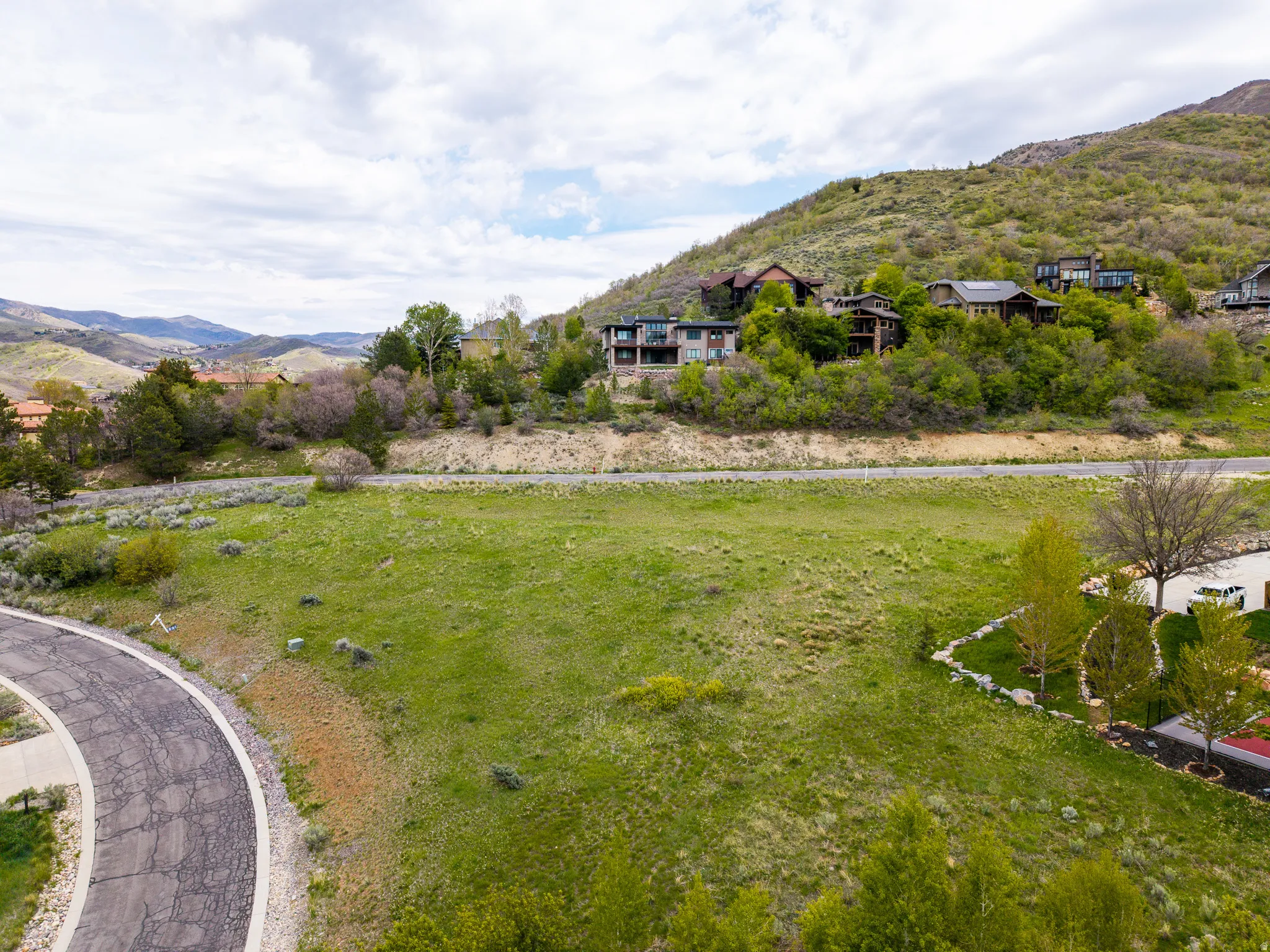 Expansive green lot with established hillside residences in the background