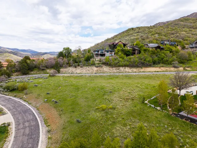 Expansive green lot with established hillside residences in the background